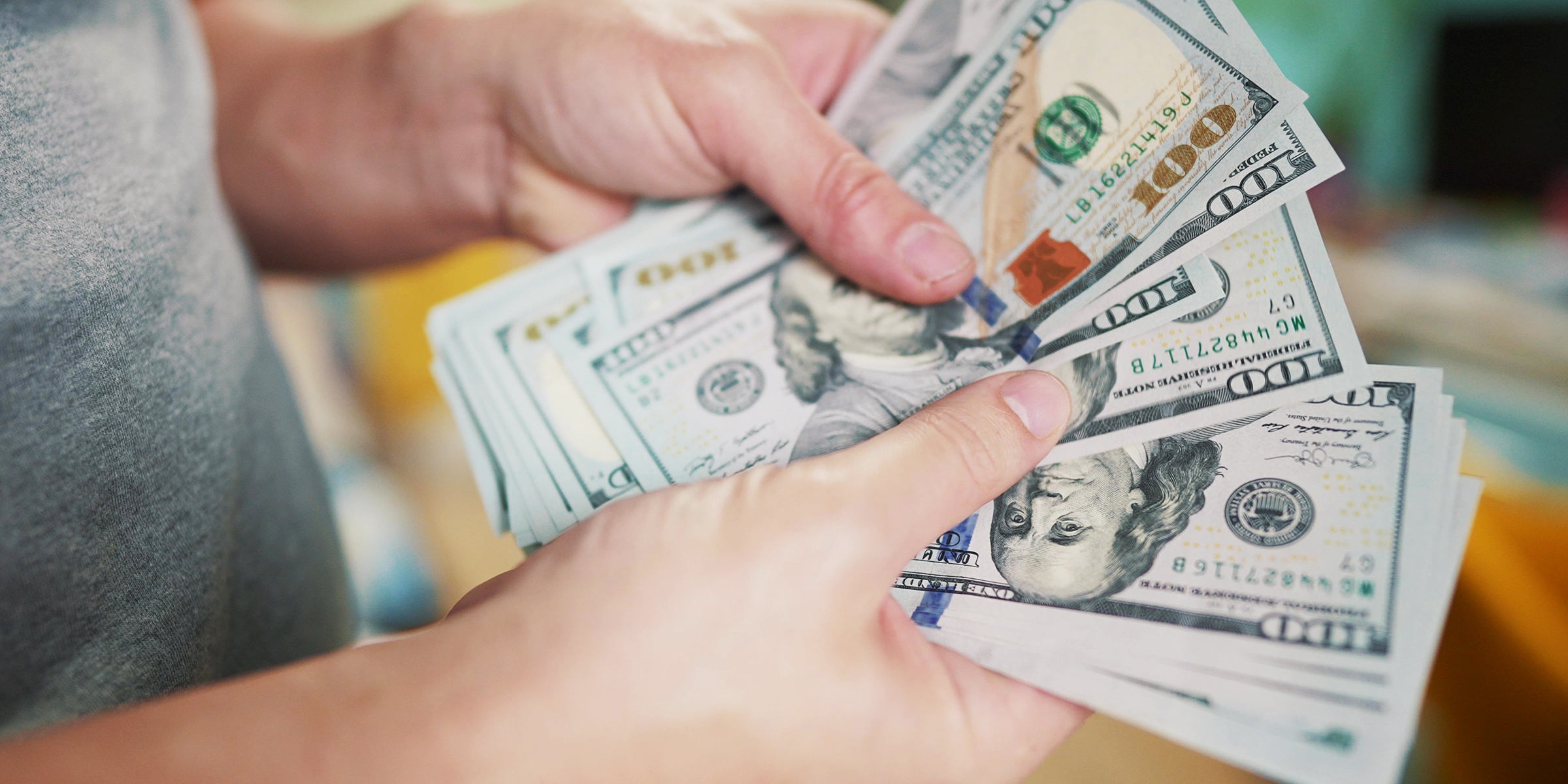 A person holding and counting a stack of $100 bills | Source: Shutterstock