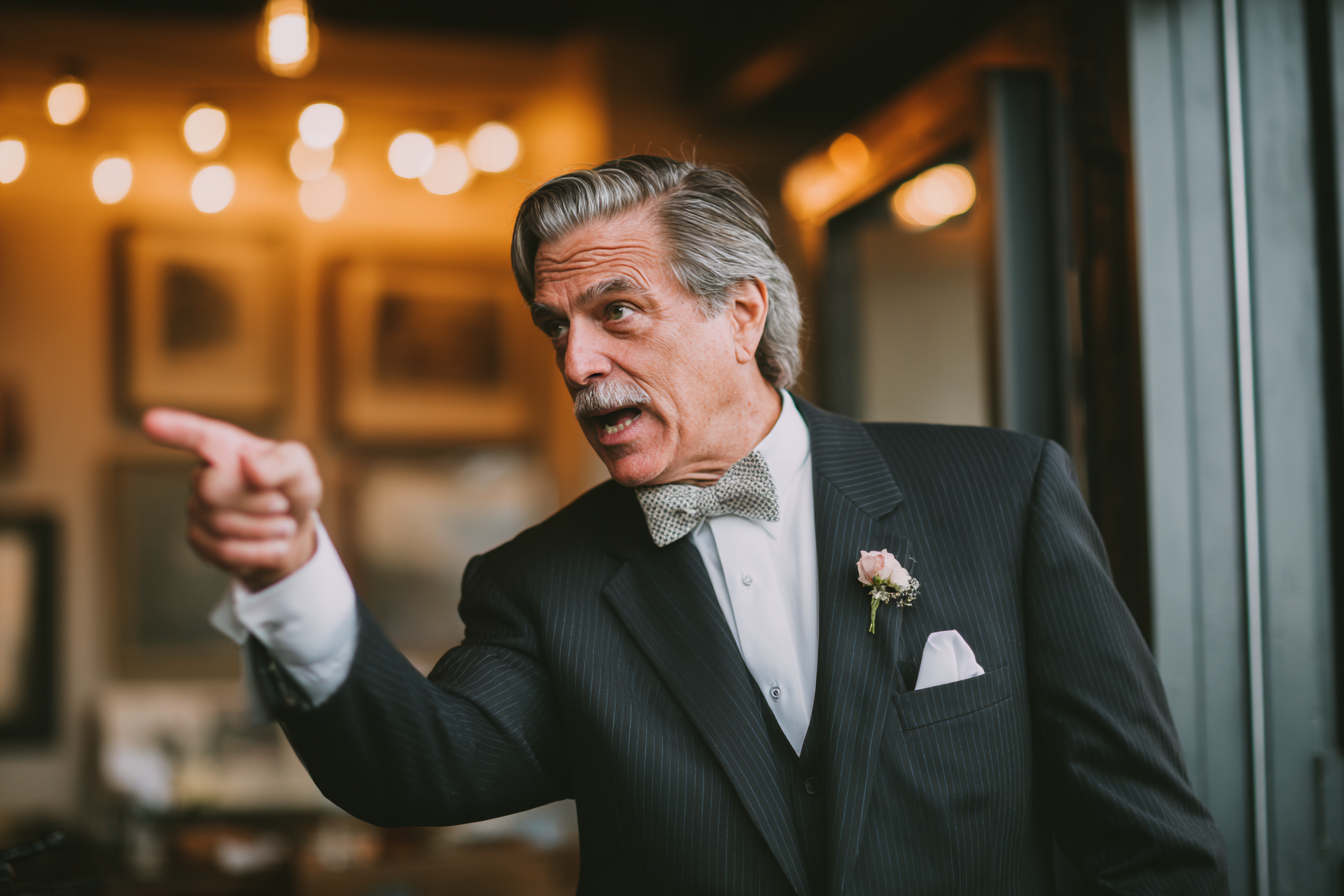 A man speaking sternly during a wedding reception | Source: Midjourney