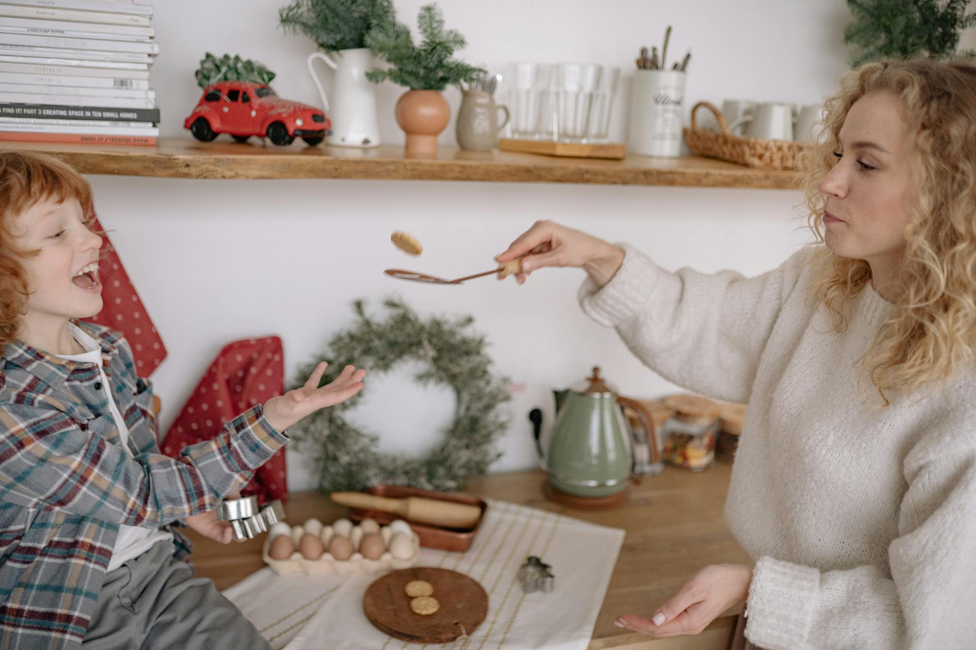 A woman flipping cookies on a ladle while having fun with her young boy | Source: Pexels
