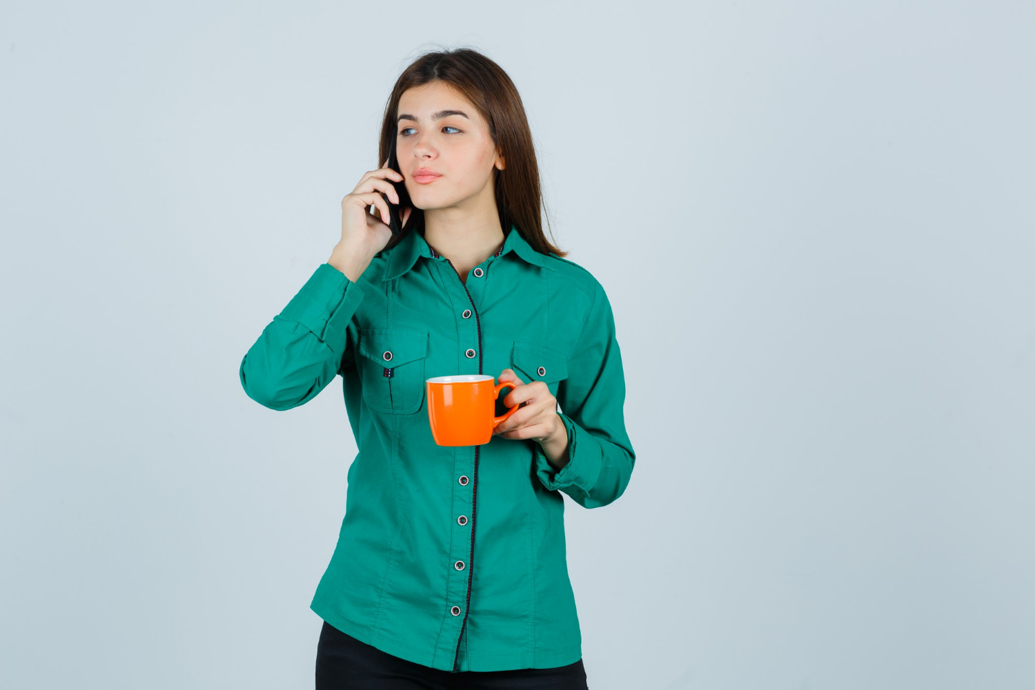 A woman talking on the phone while holding an orange cup | Source: Freepik