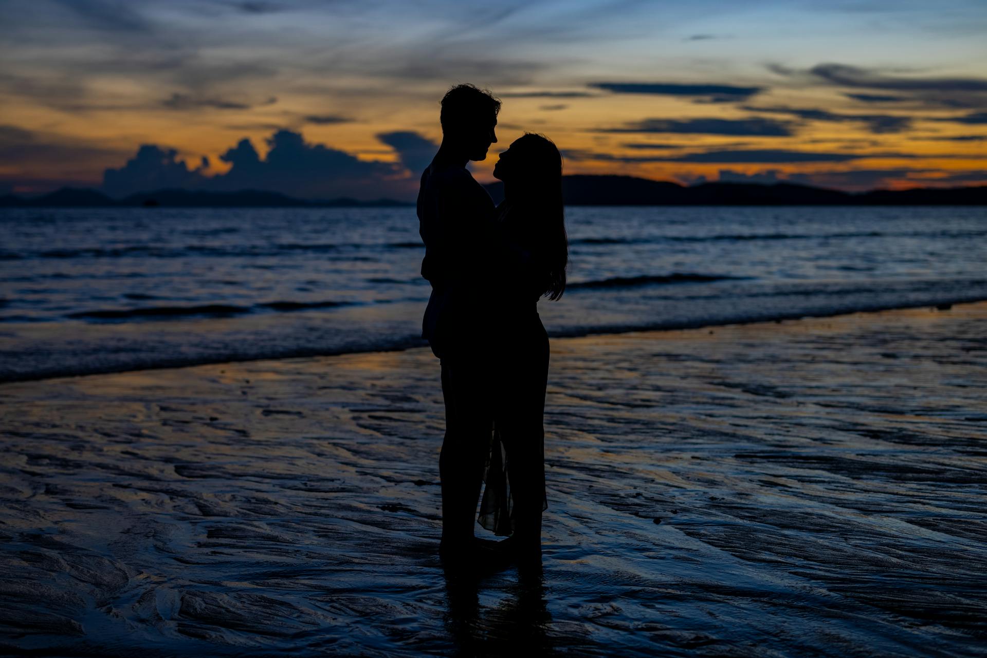 Silueta de una pareja de enamorados abrazándose en la playa al atardecer | Fuente: Pexels