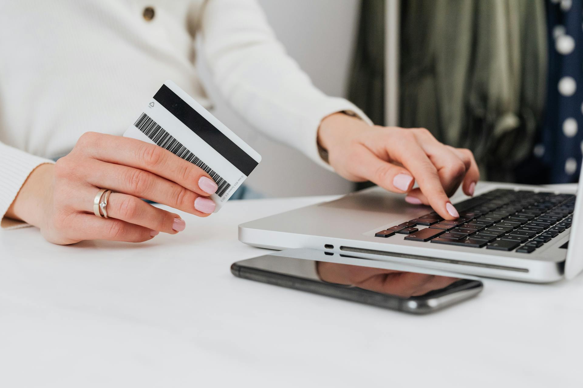 A woman holding a credit card while using her laptop | Source: Pexels