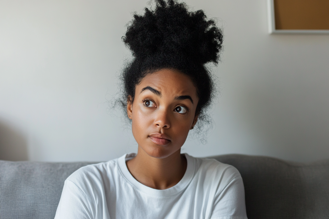 A woman sitting on a couch, looking to the side | Source: Midjourney