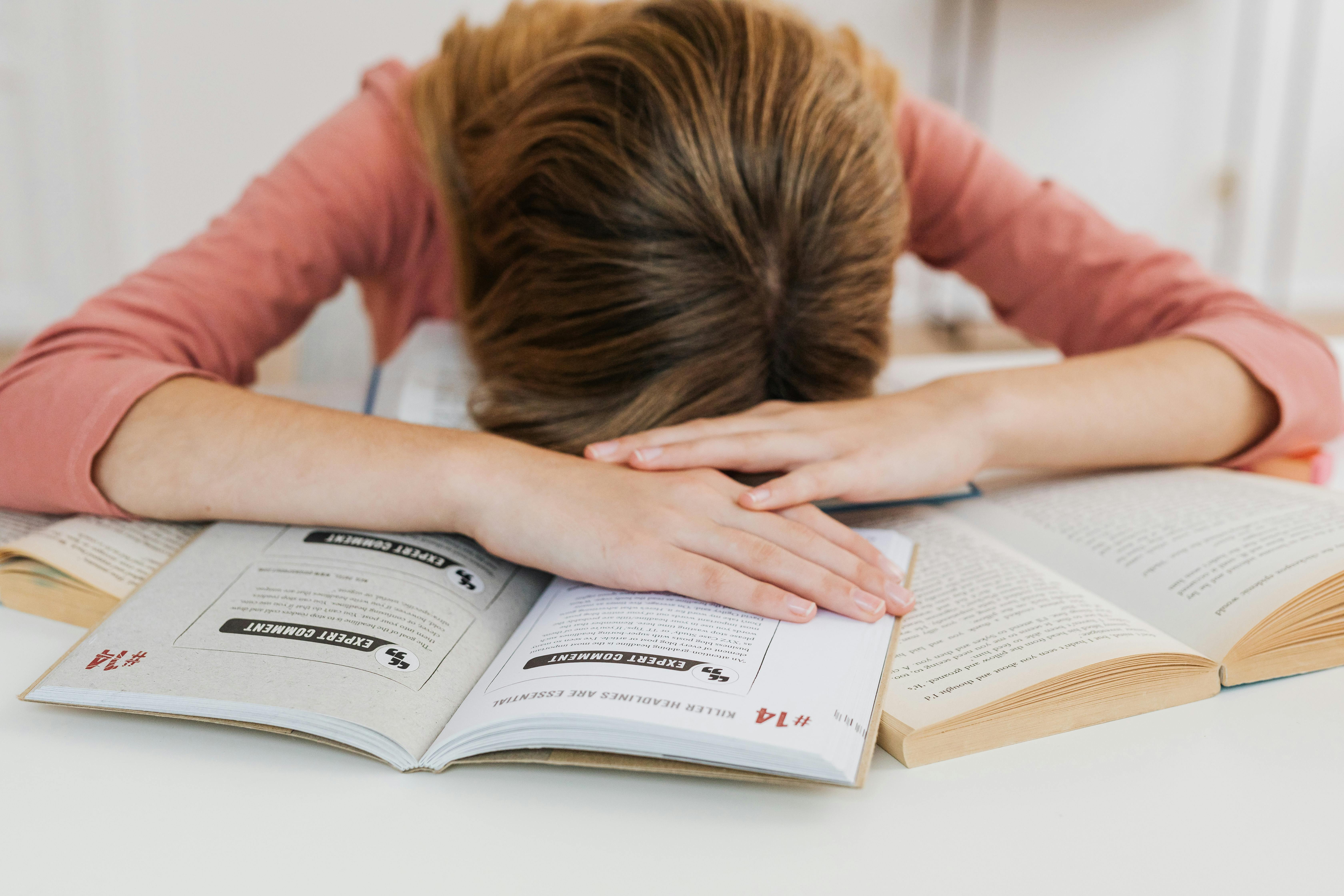 A stressed girl lying on her books | Source: Pexels