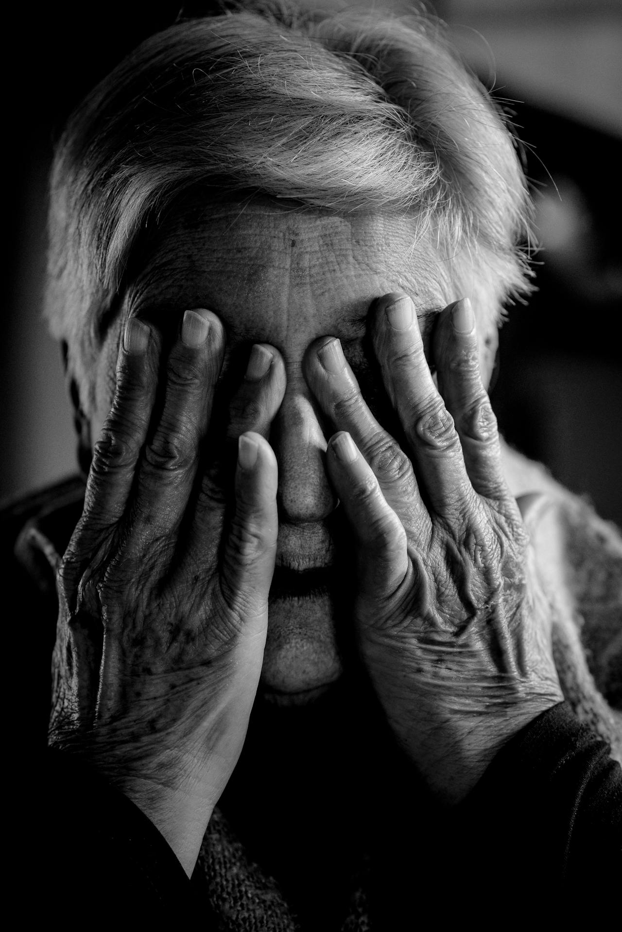 A heartbroken older woman covering her face | Source: Pexels