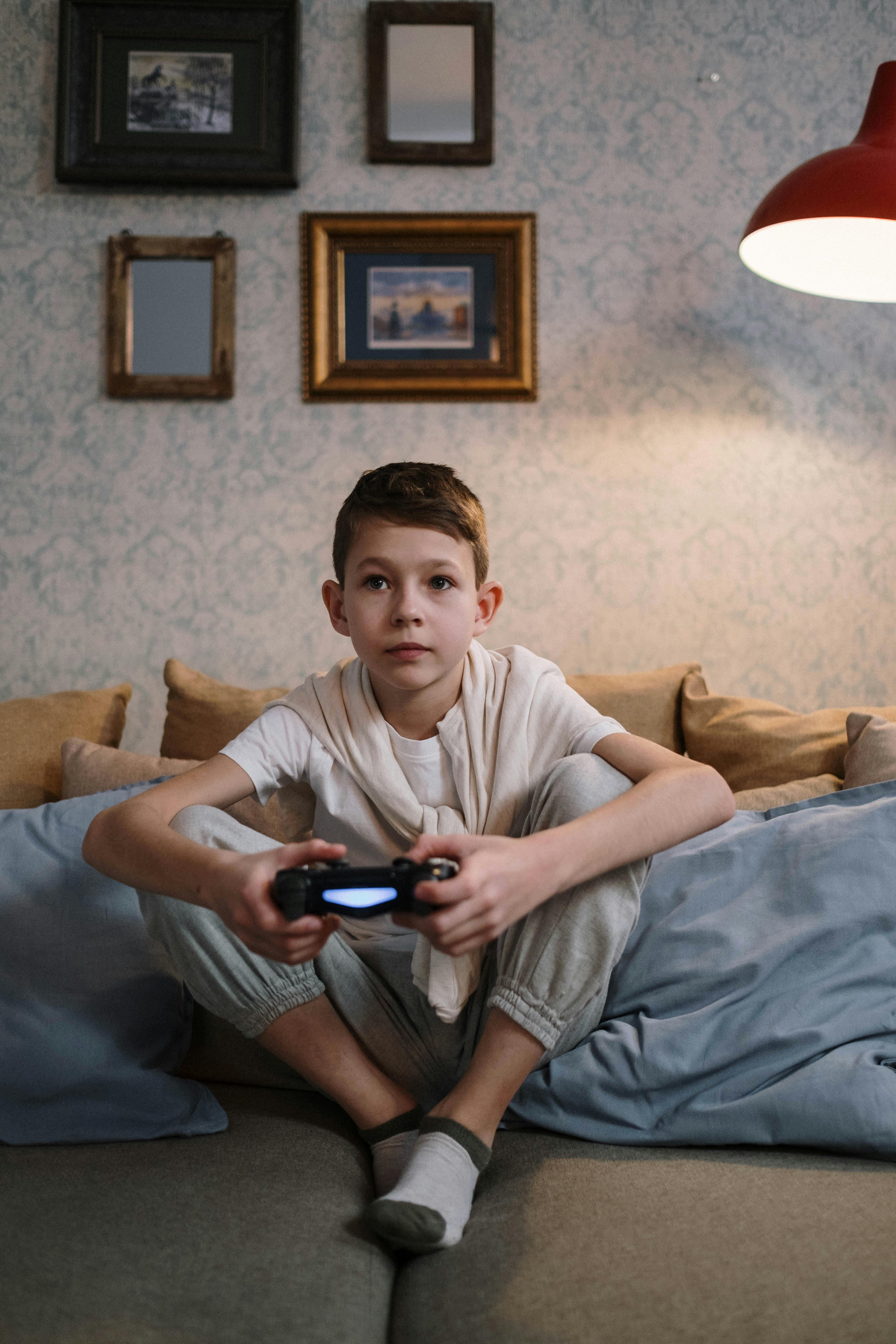 Arthur sitting on the sofa, playing a video game and looking thoughtful | Source: Pexels