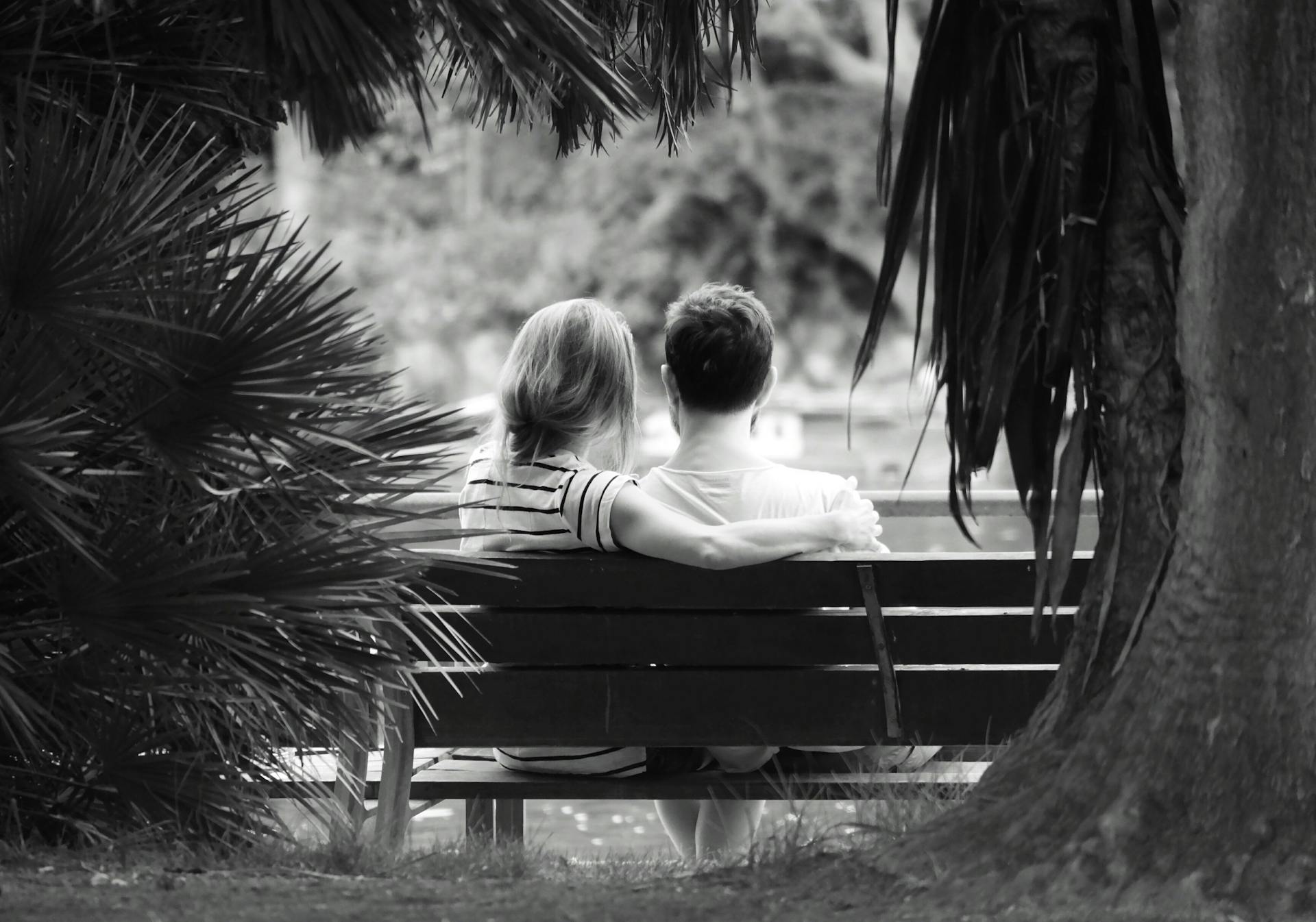 Grayscale shot of a couple sitting on a wooden bench | Source: Pexels