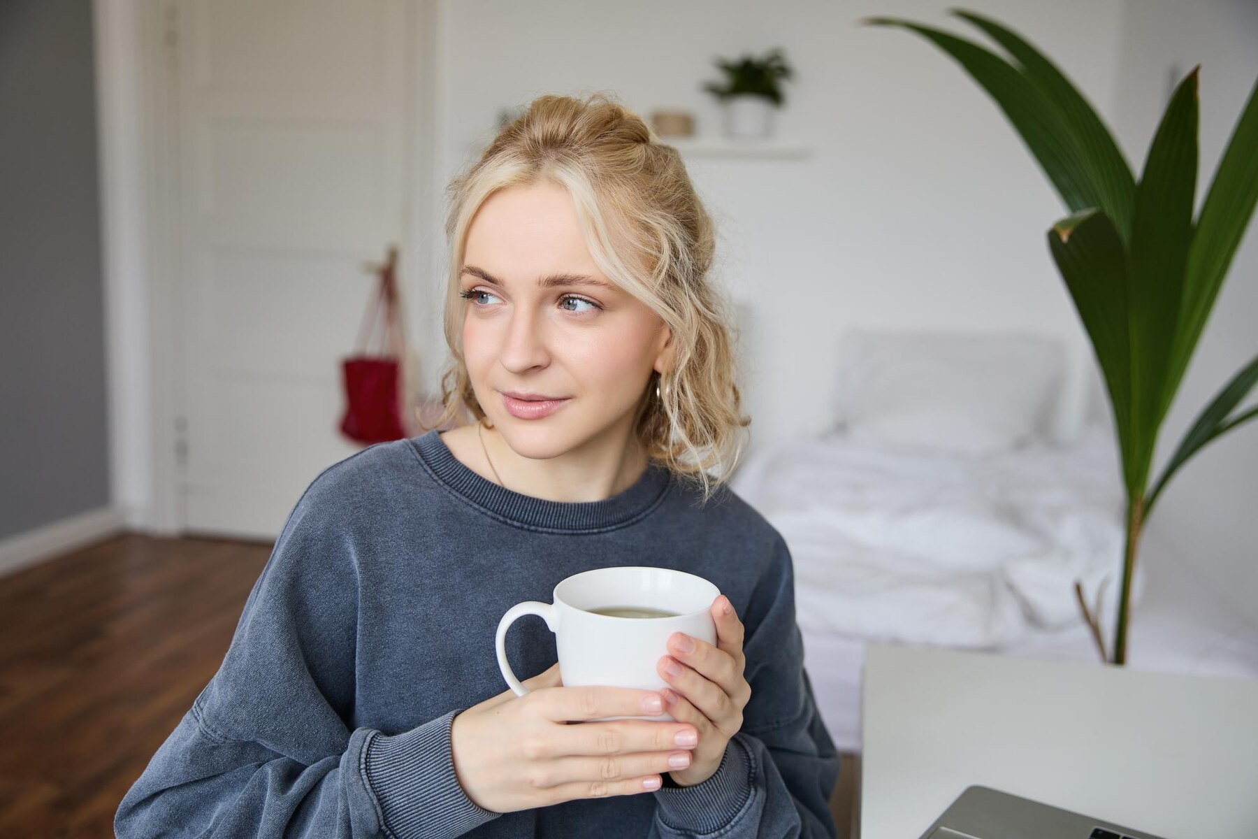 A woman looking to her side while drinking coffee | Source: Freepik