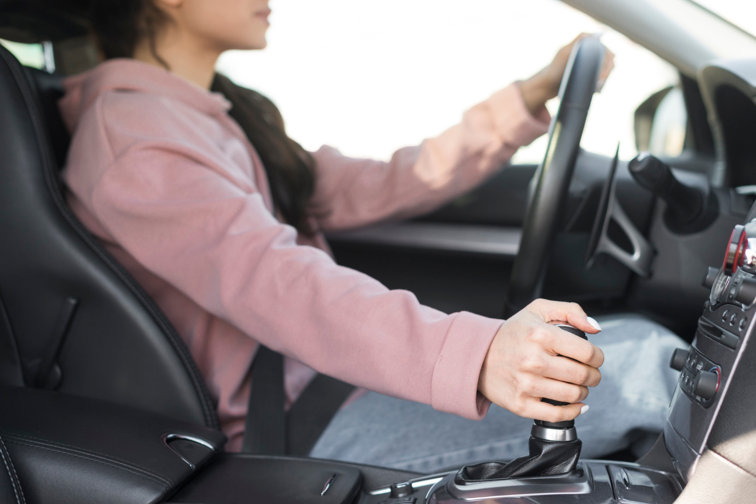 A woman switching gears while driving her car | Source: Freepik