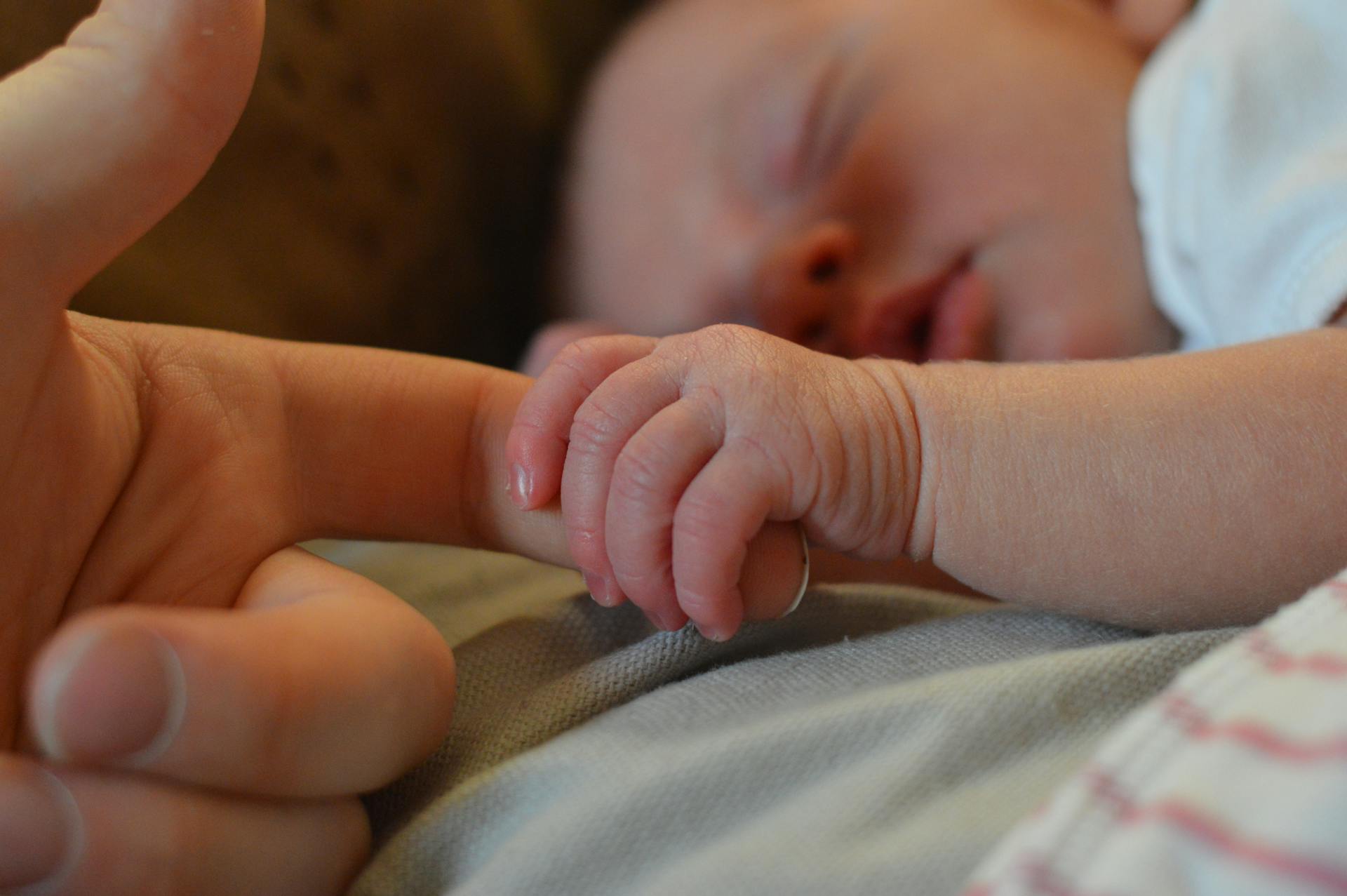 A baby holding a person's finger | Source: Pexels