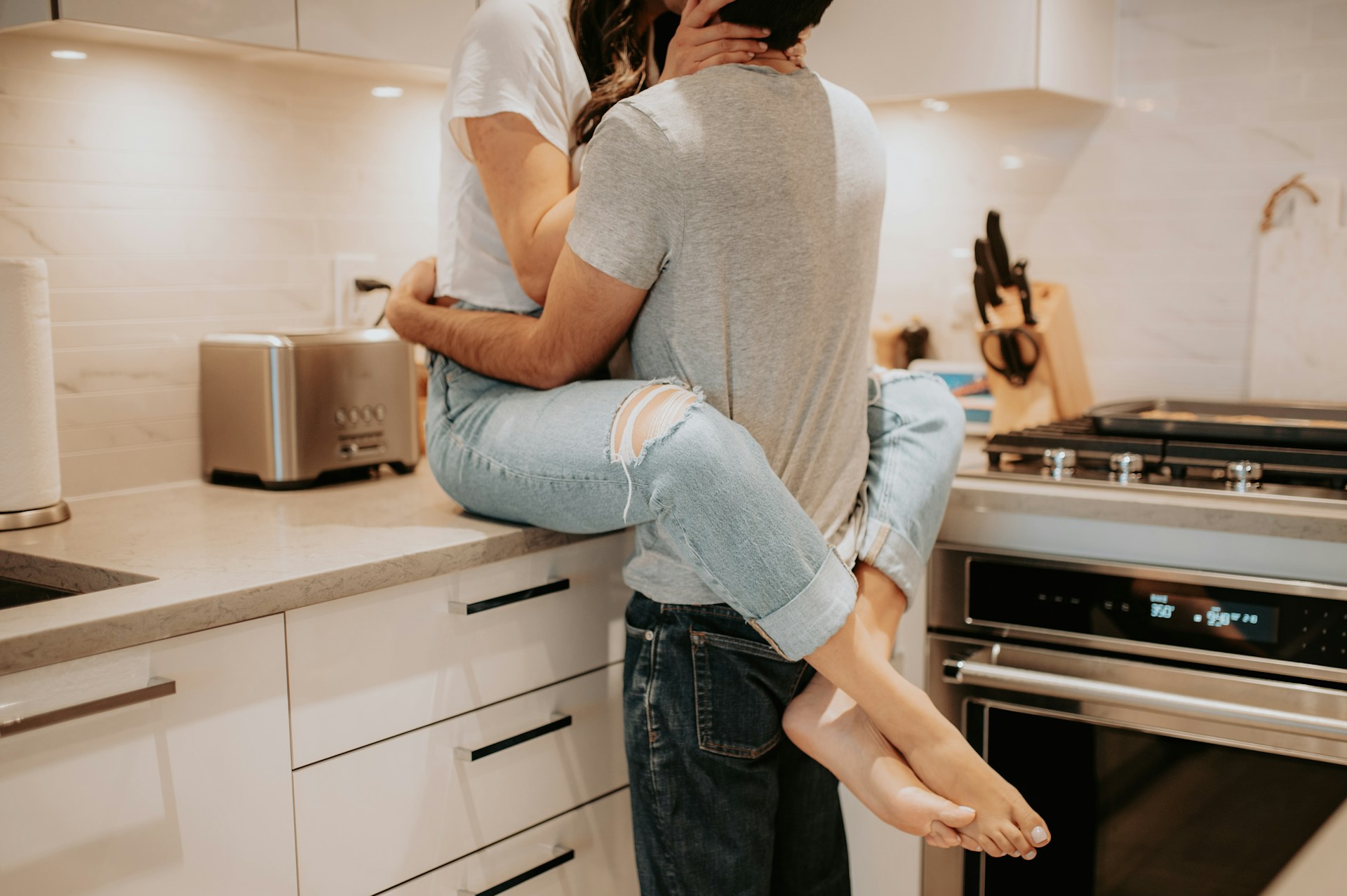 A romantic couple hugging each other in the kitchen | Source: Unsplash