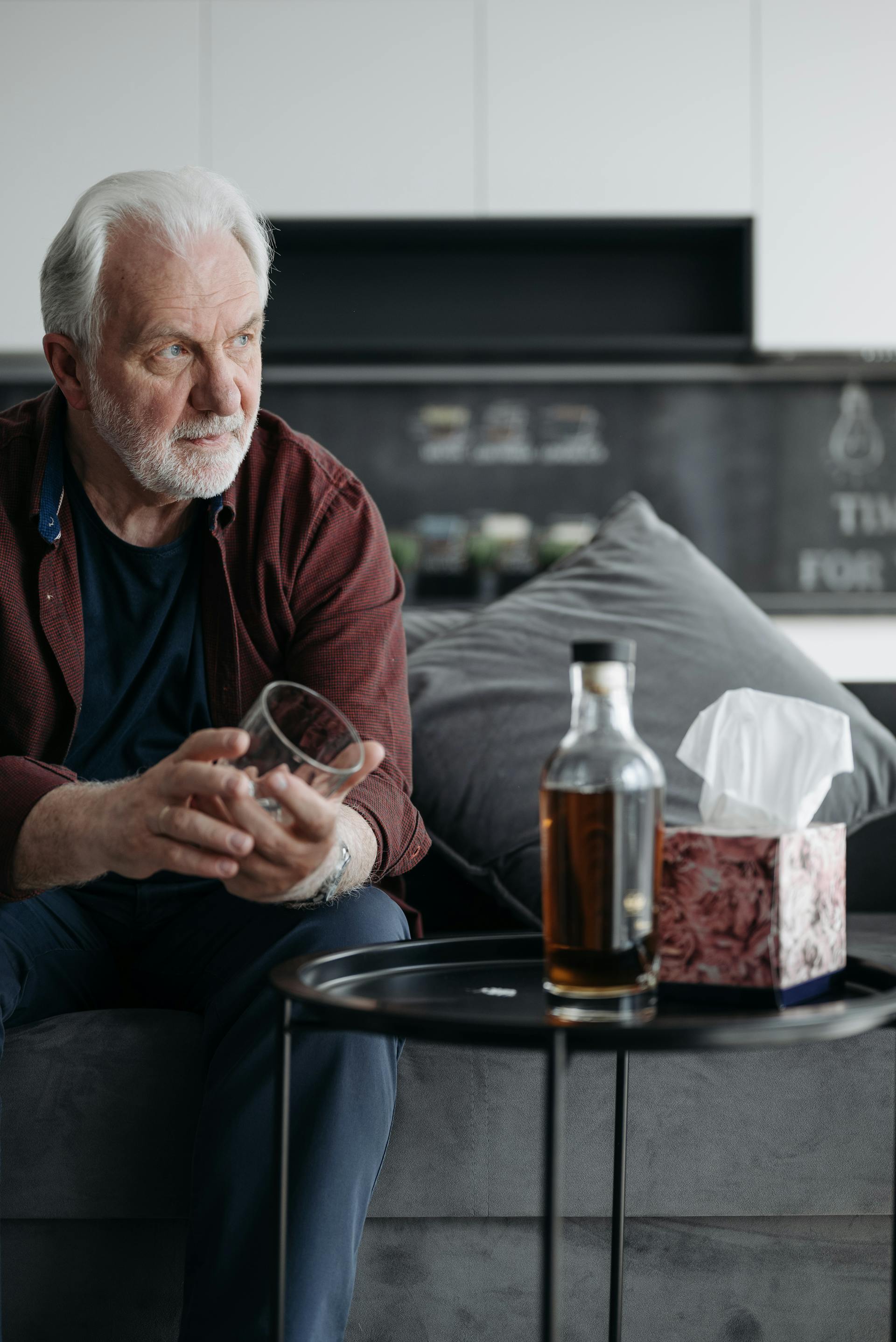 A man holding a glass with a bottle of beer lying in front of him | Source: Pexels