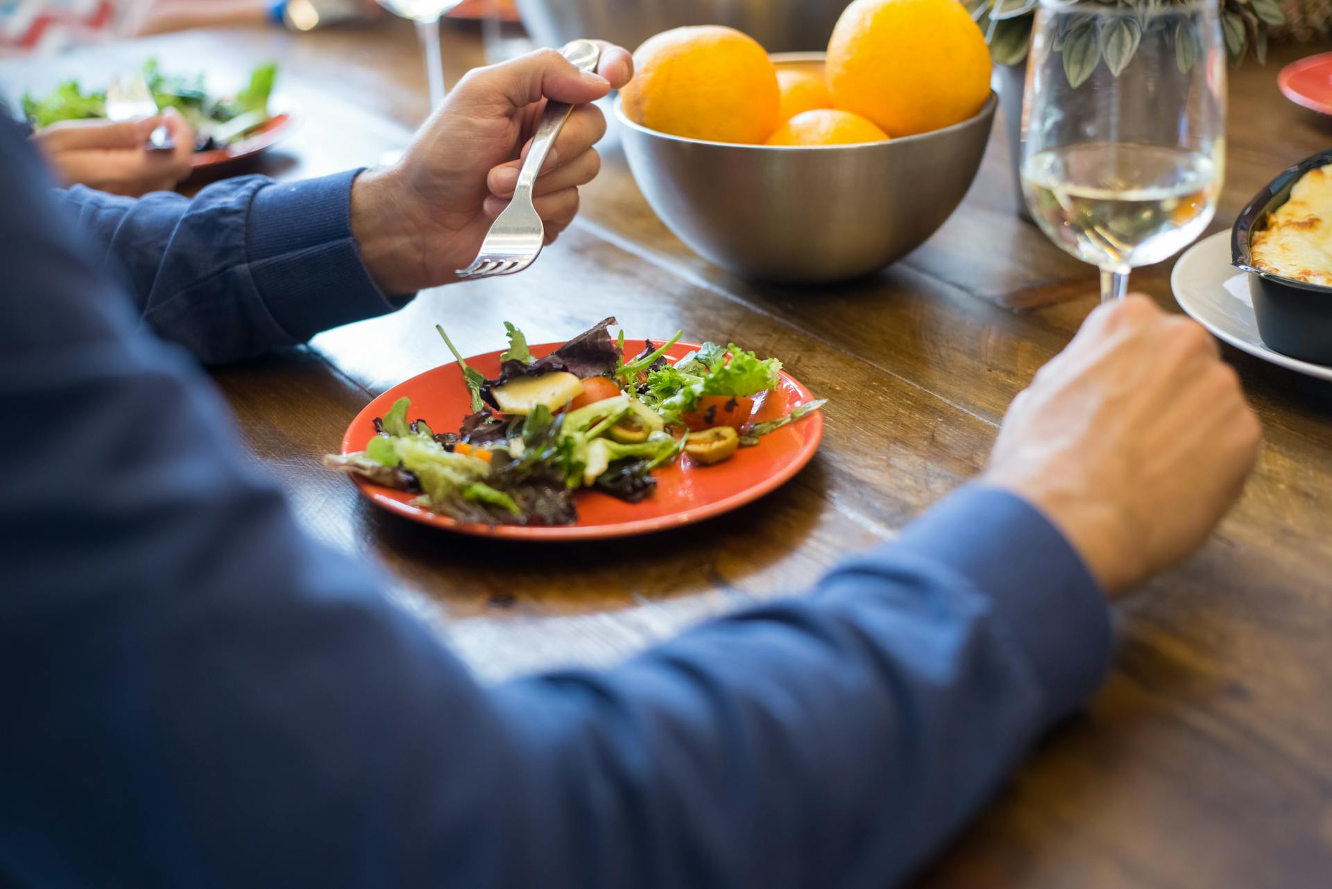 A person seated at a table and eating salad | Source: Pexels