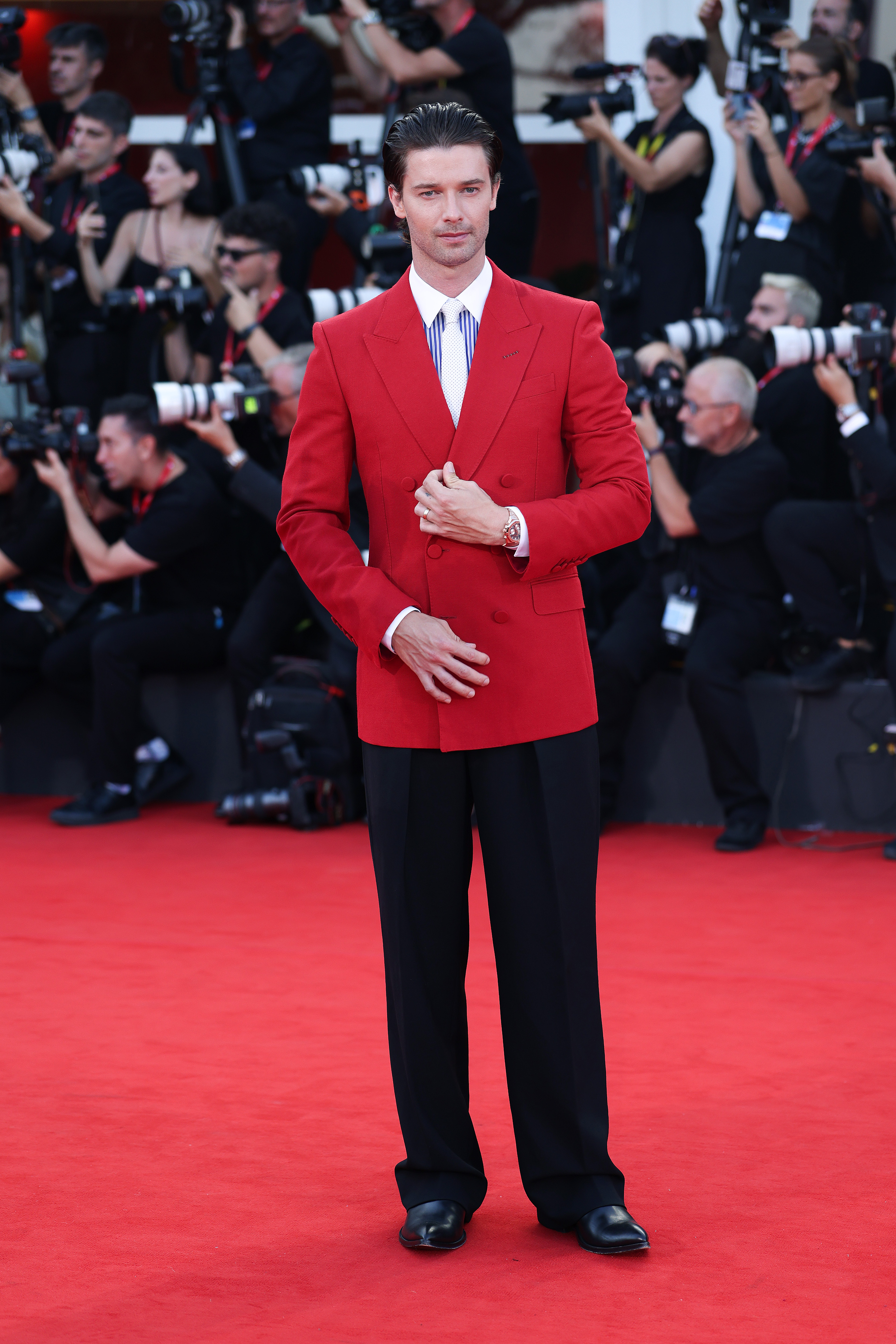 Patrick Schwarzenegger attends The Bunker screening during the 83rd Venice International Film Festival in Venice, Italy, in September 2026, wearing a striking red double-breasted blazer over a blue-striped shirt and white textured tie. | Source: Getty Images