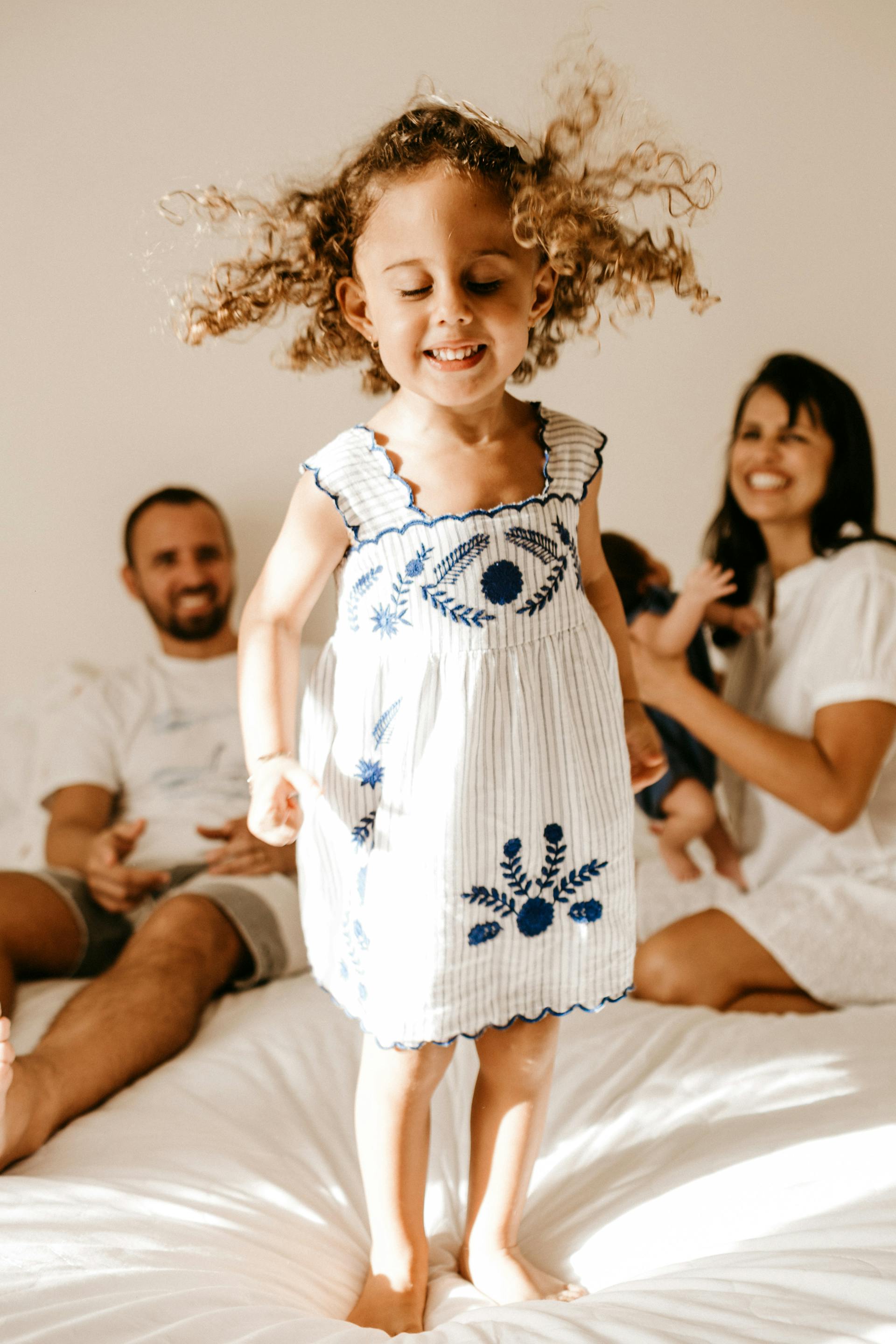 Uma menina feliz em pé em cima de uma cama | Fonte: Midjourney