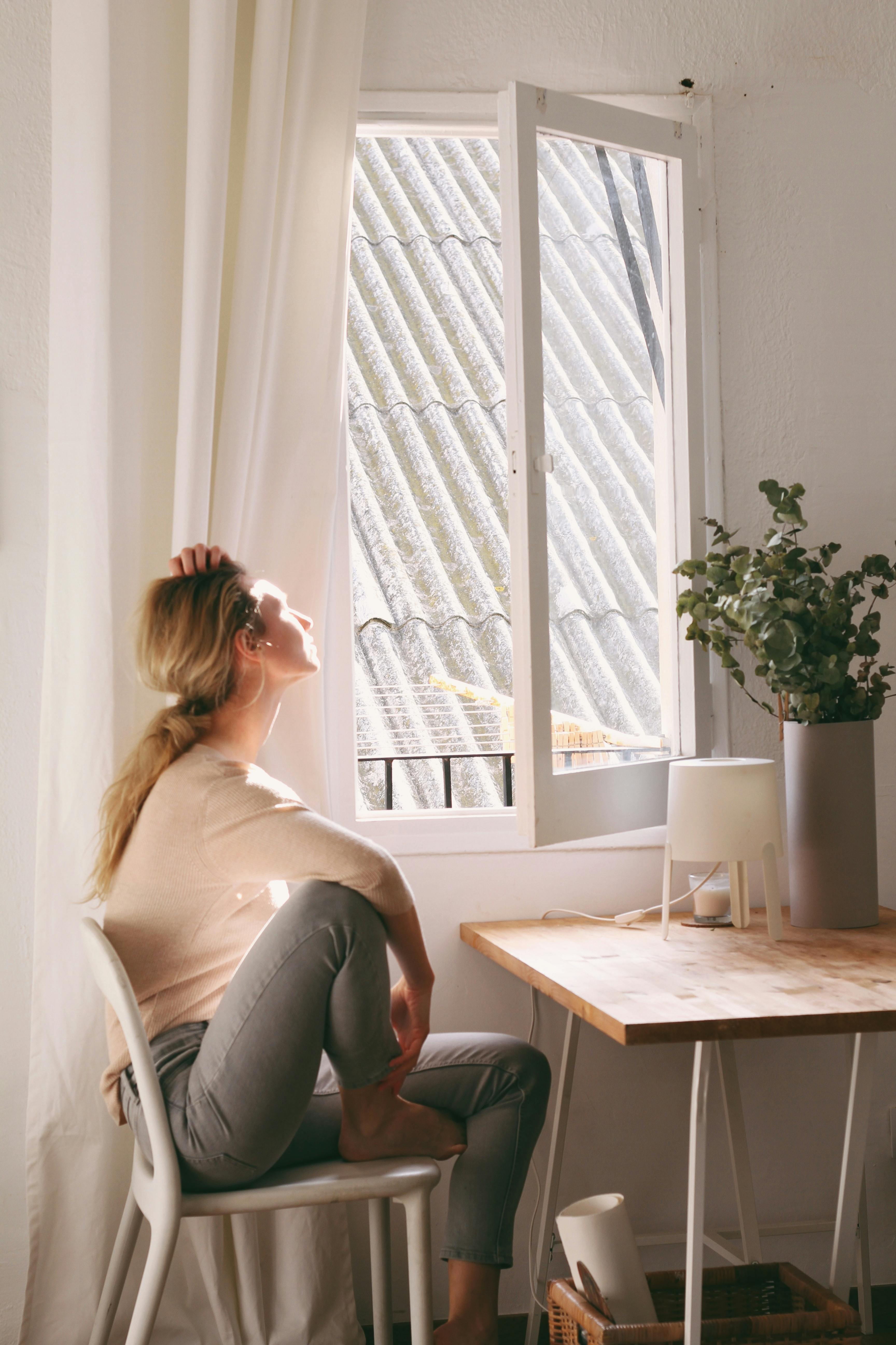 A woman looks thoughtfully out of a window | Source: Pexels