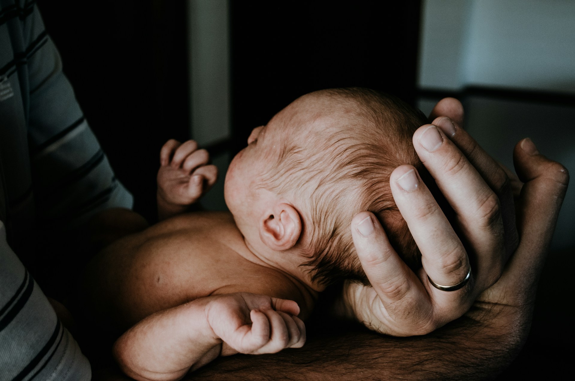 An emotionally overwhelmed man holding a newborn baby | Source: Unsplash