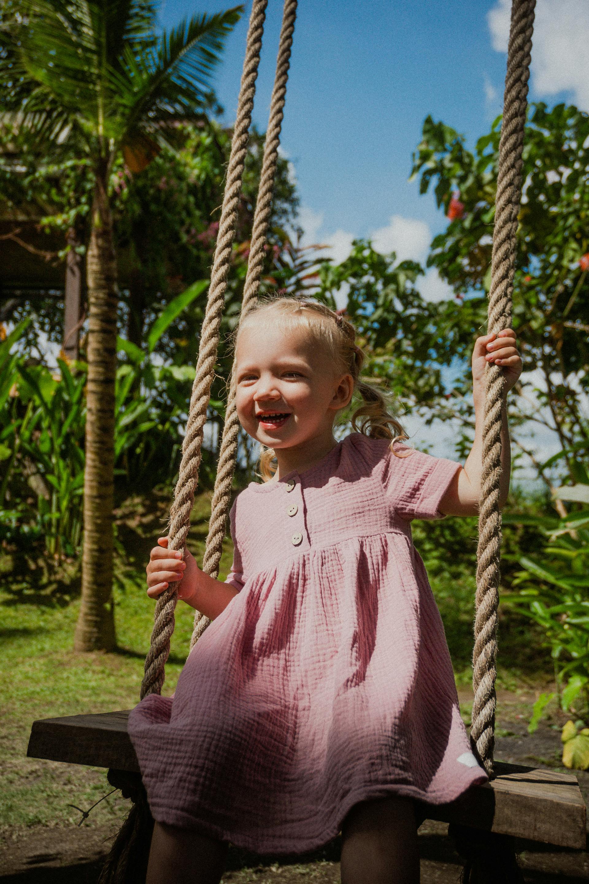 A smiling little girl on a rope swing | Source: Pexels