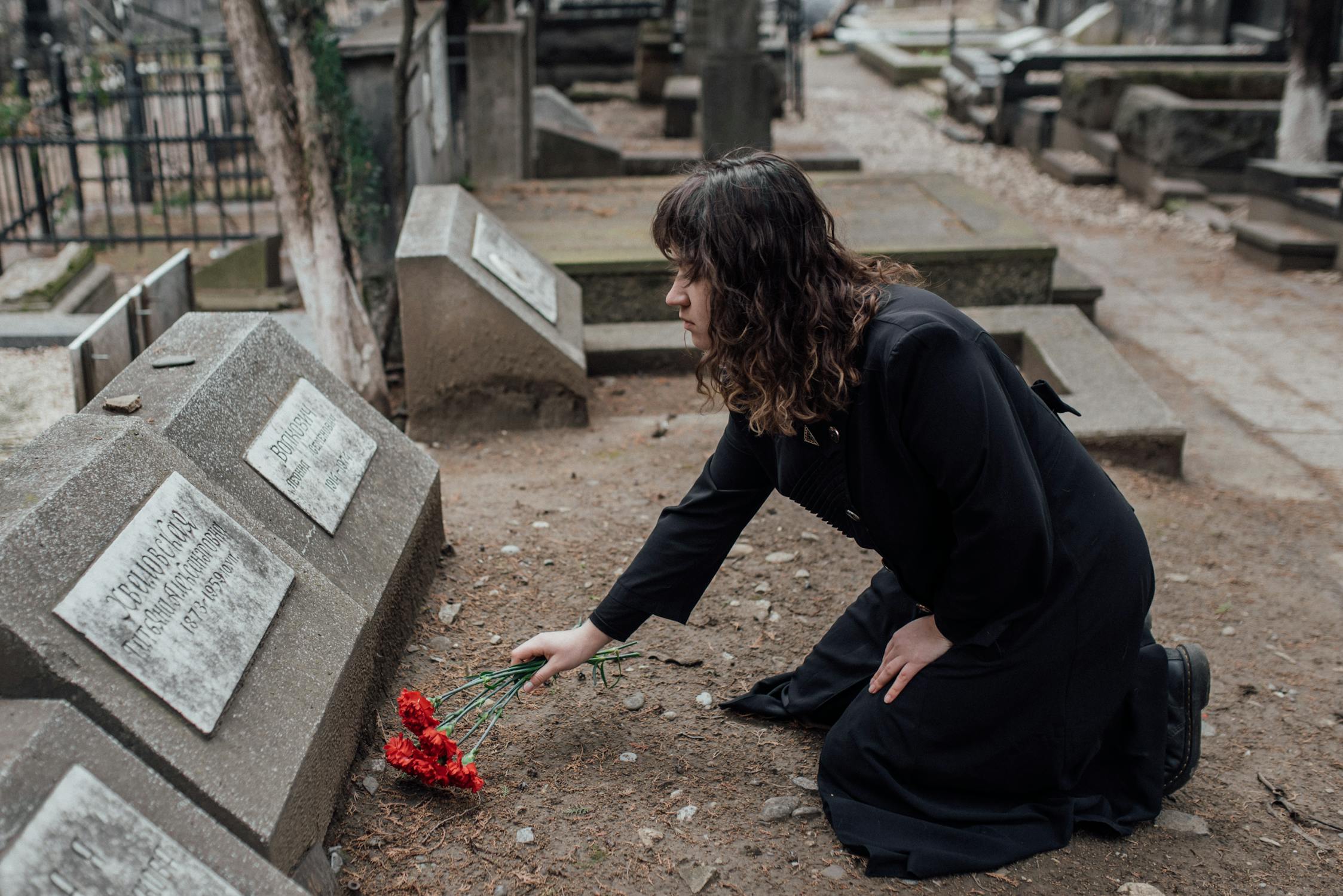 A woman laying flowers on a grave | Source: Pexels