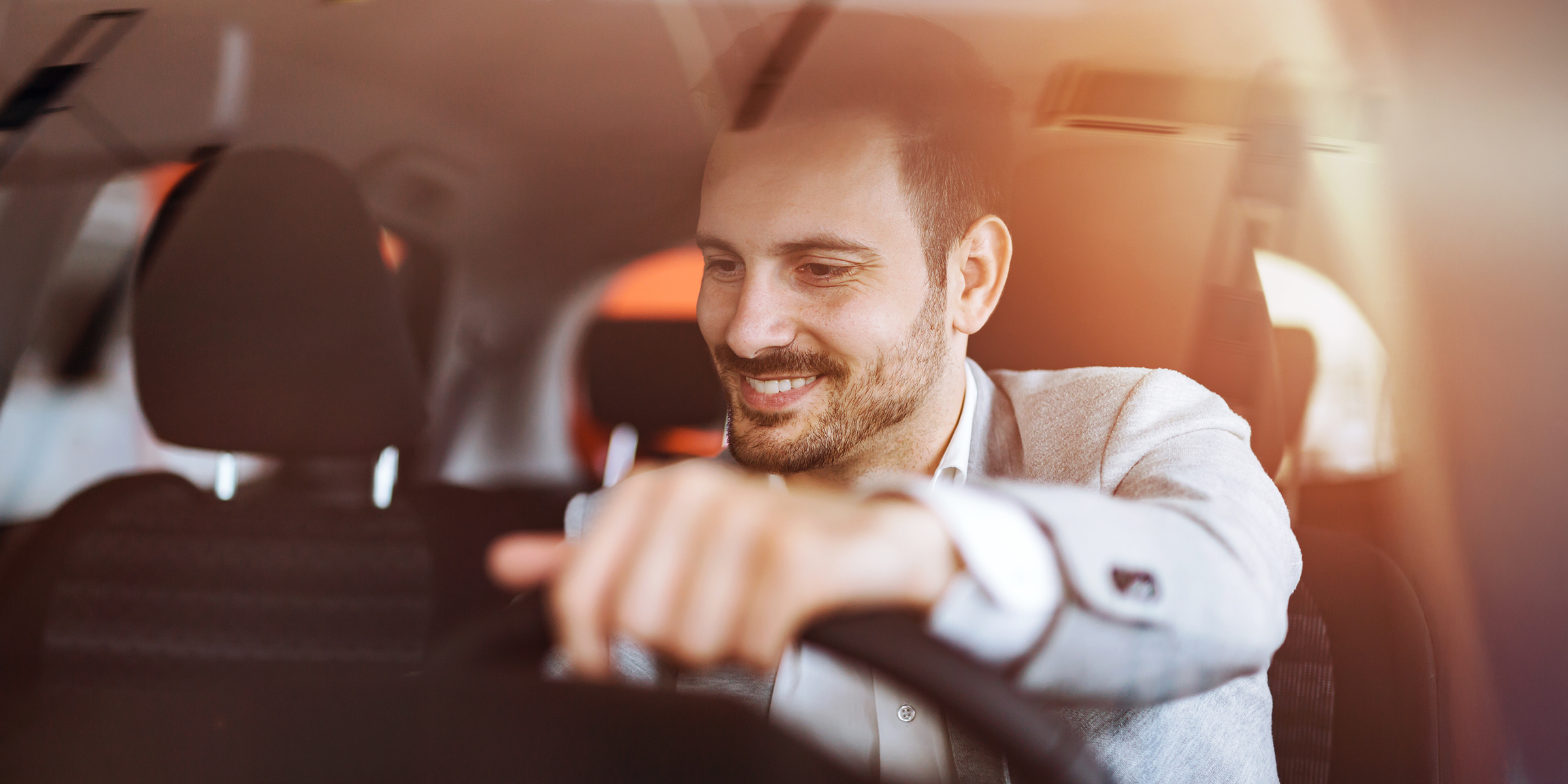 A smiling man sitting behind the wheel, enjoying the drive in his car | Source: Shutterstock