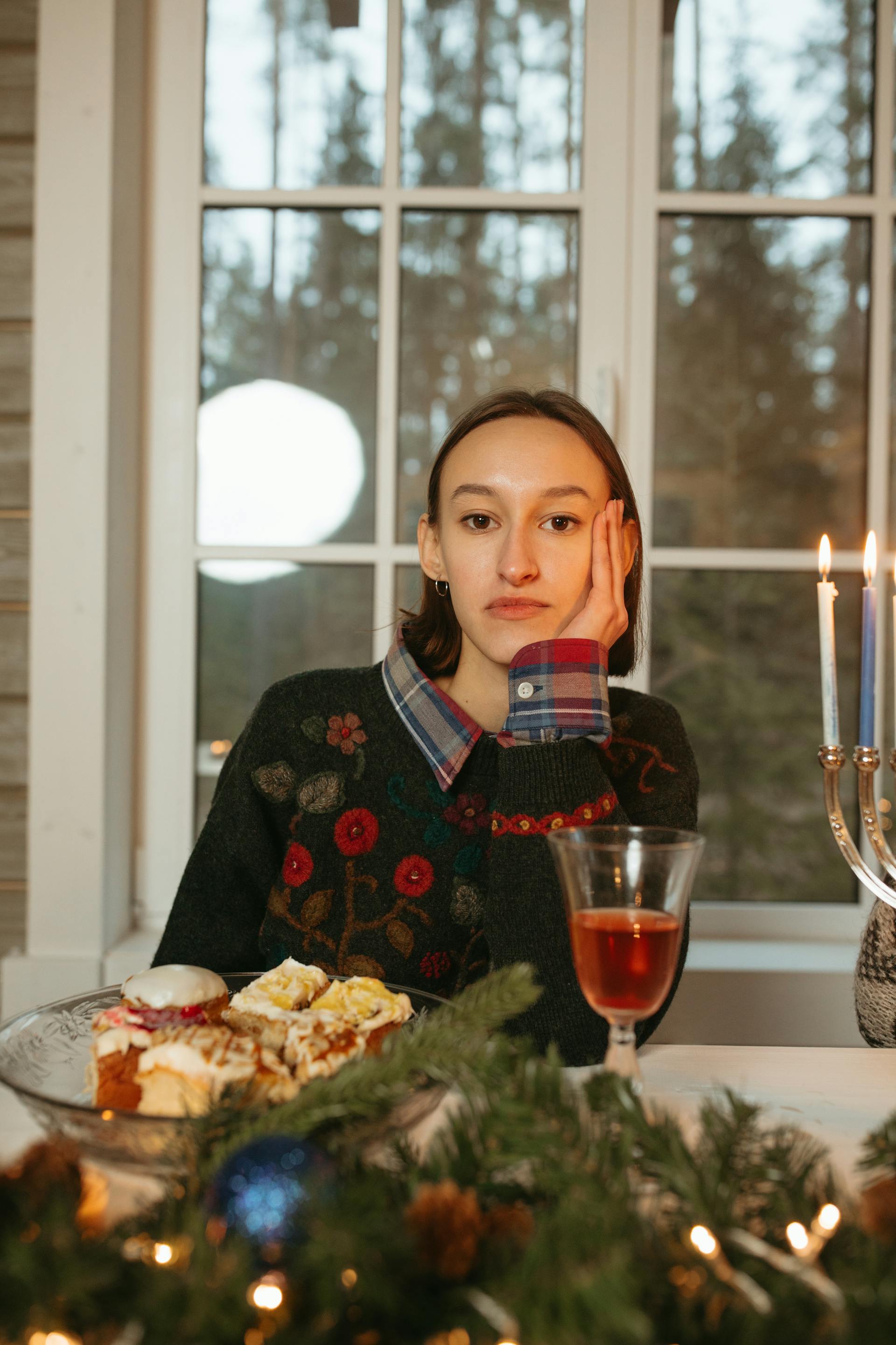 A woman sitting at a table with a plate of fruitcake | Source: Pexels