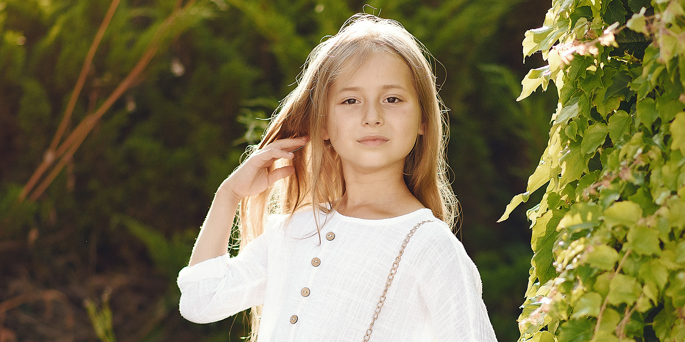 A young girl standing outdoor in a lush green landscape | Source: Freepik