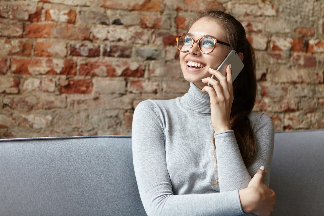 A smiling woman talking on her phone looking up ⏐ Source: Freepik