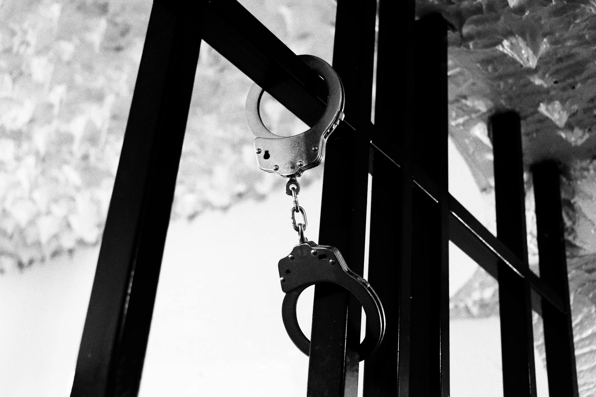 Handcuffs on steel bars | Source: Pexels