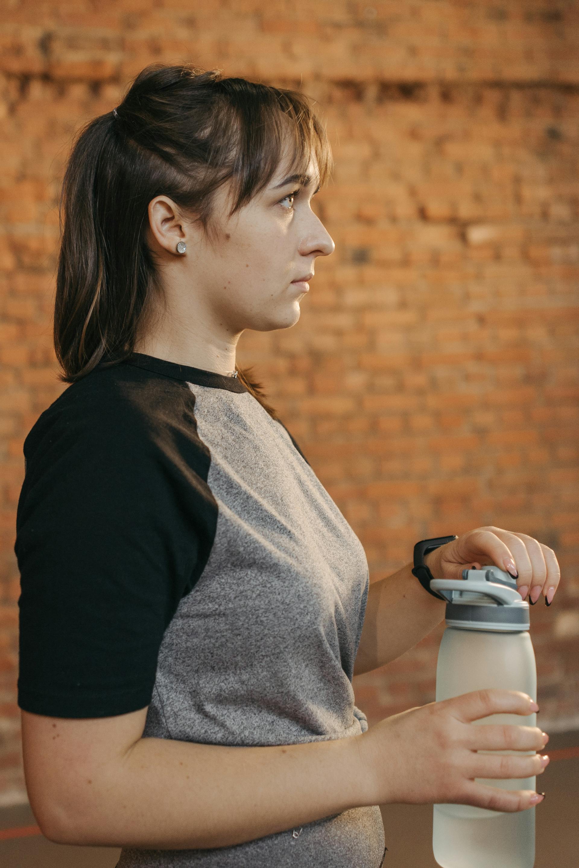 A woman in work-out clothes holding a water bottle | Source: Pexels
