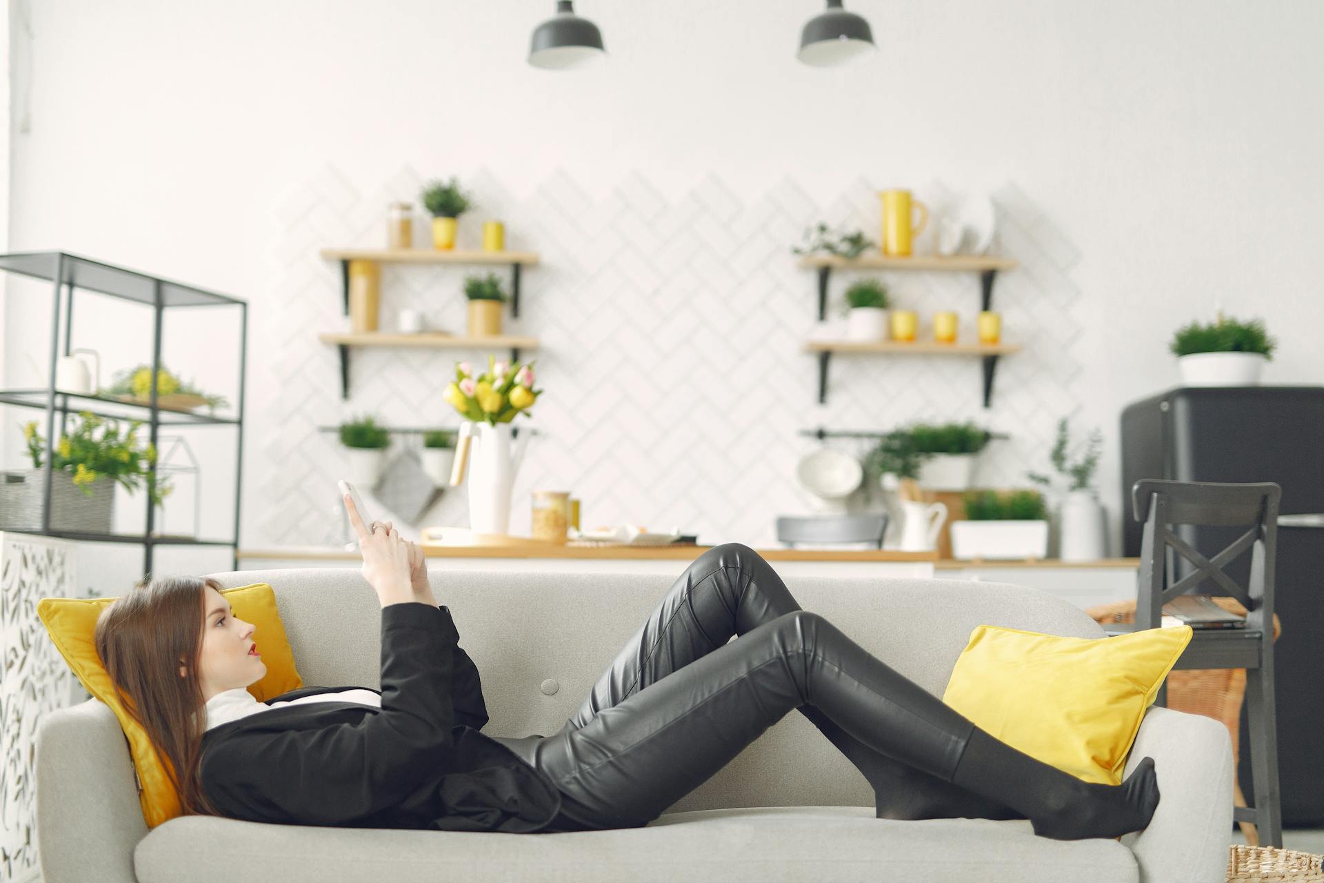 A woman lying on the couch and using her phone | Source: Pexels