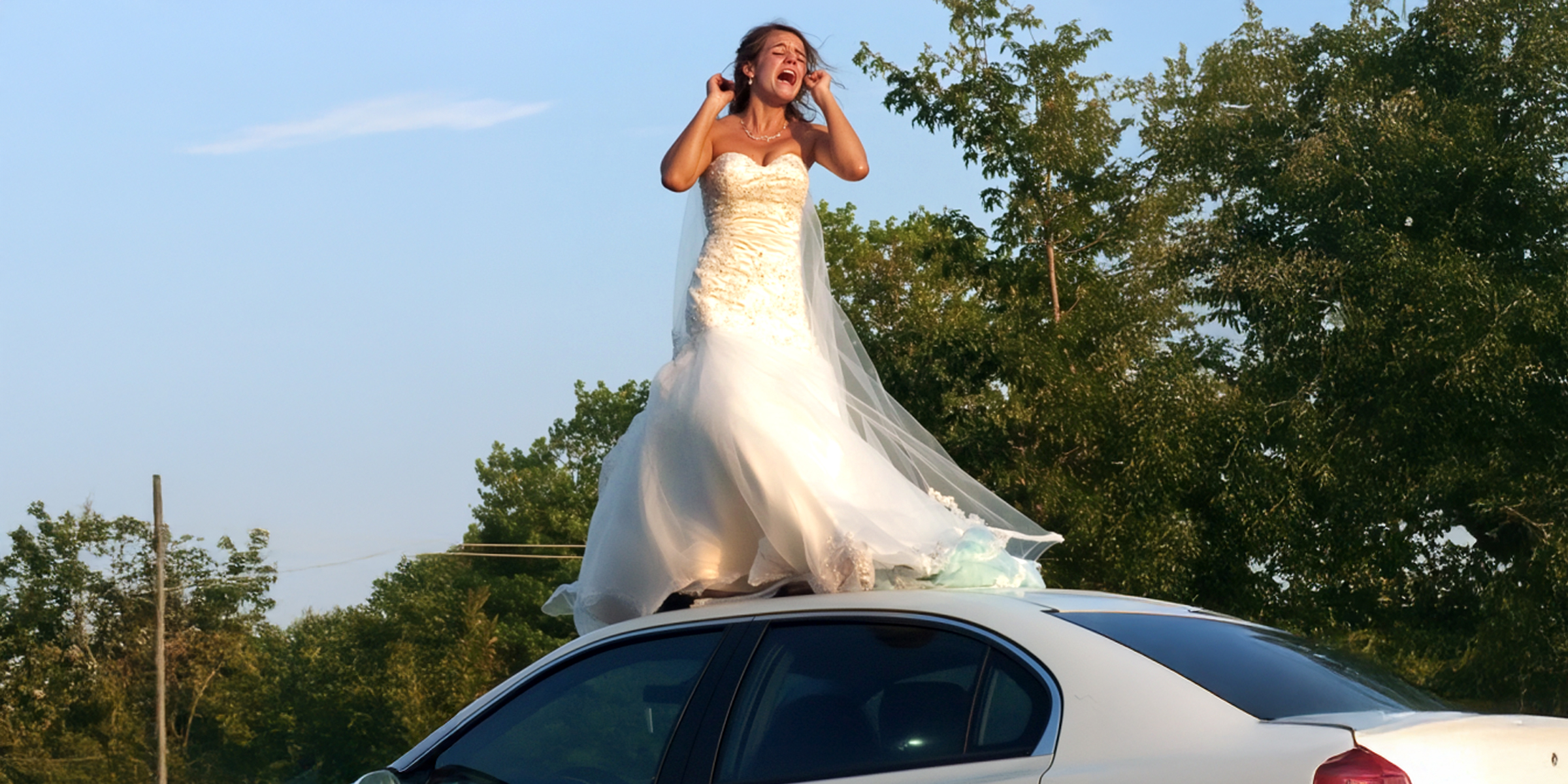 A woman in a wedding dress standing and crying on the roof of a car | Source: Amomama