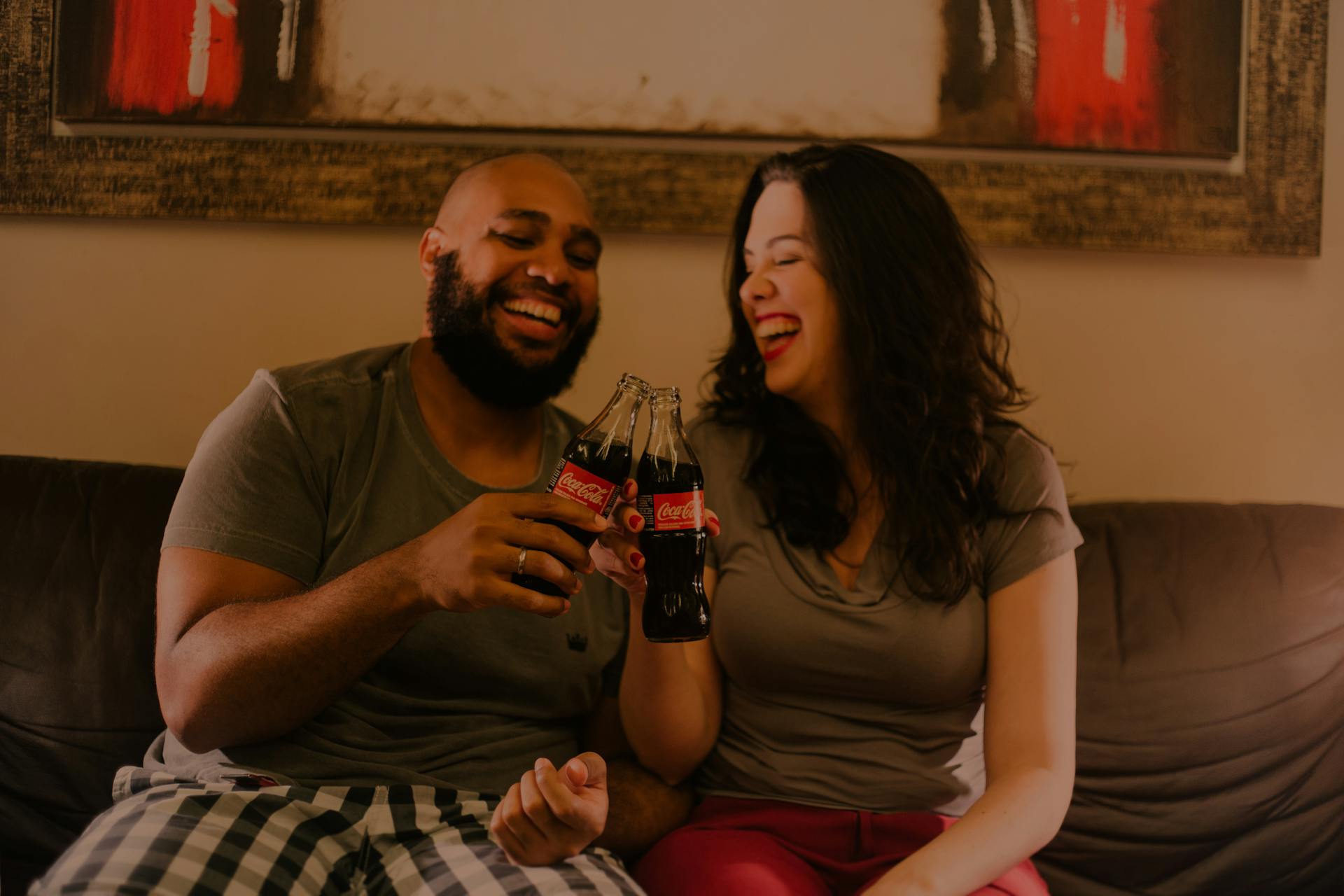 A couple laugh while holding soft drink bottles | Source: Pexels