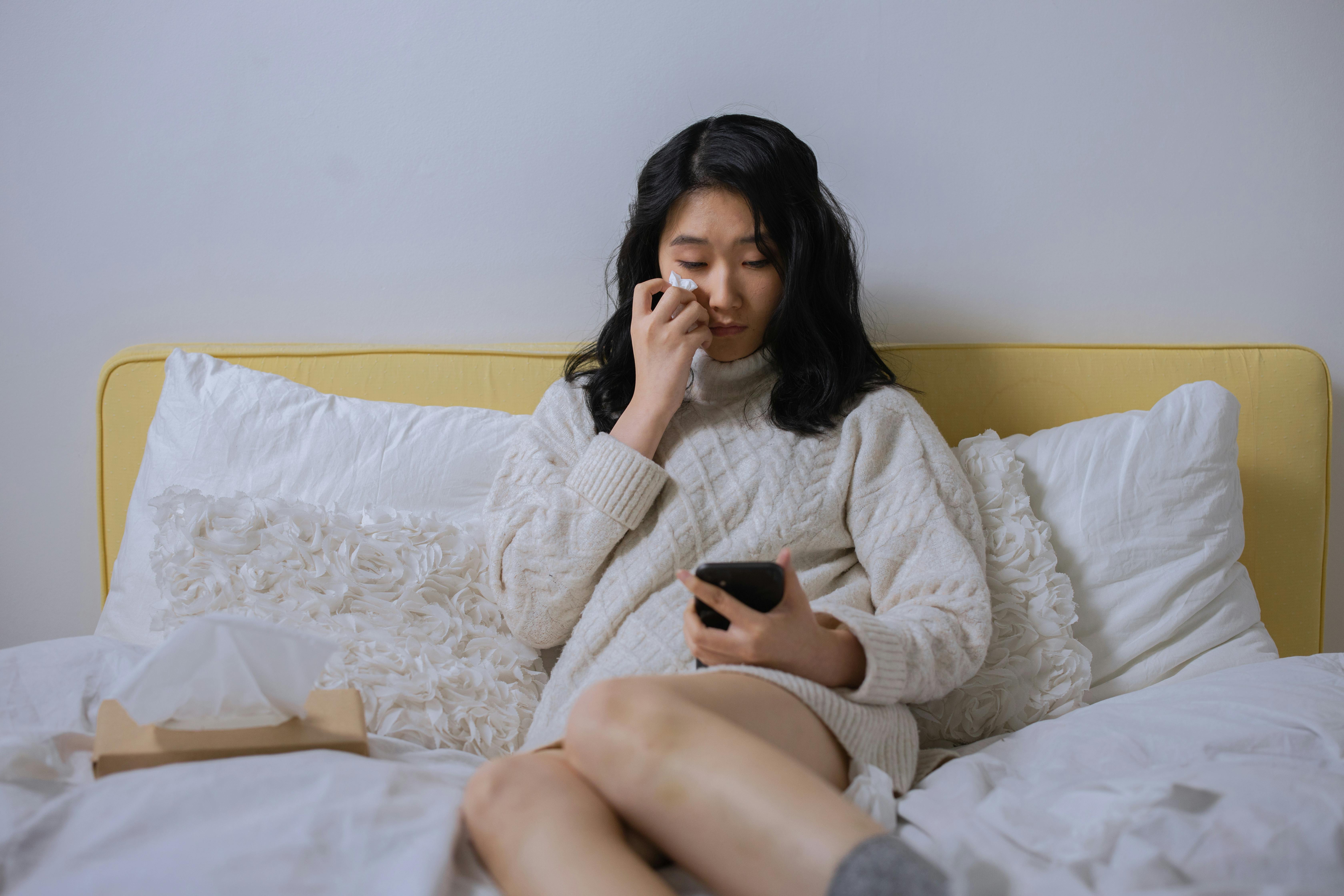 A woman crying while looking at her cellphone | Source: Pexels