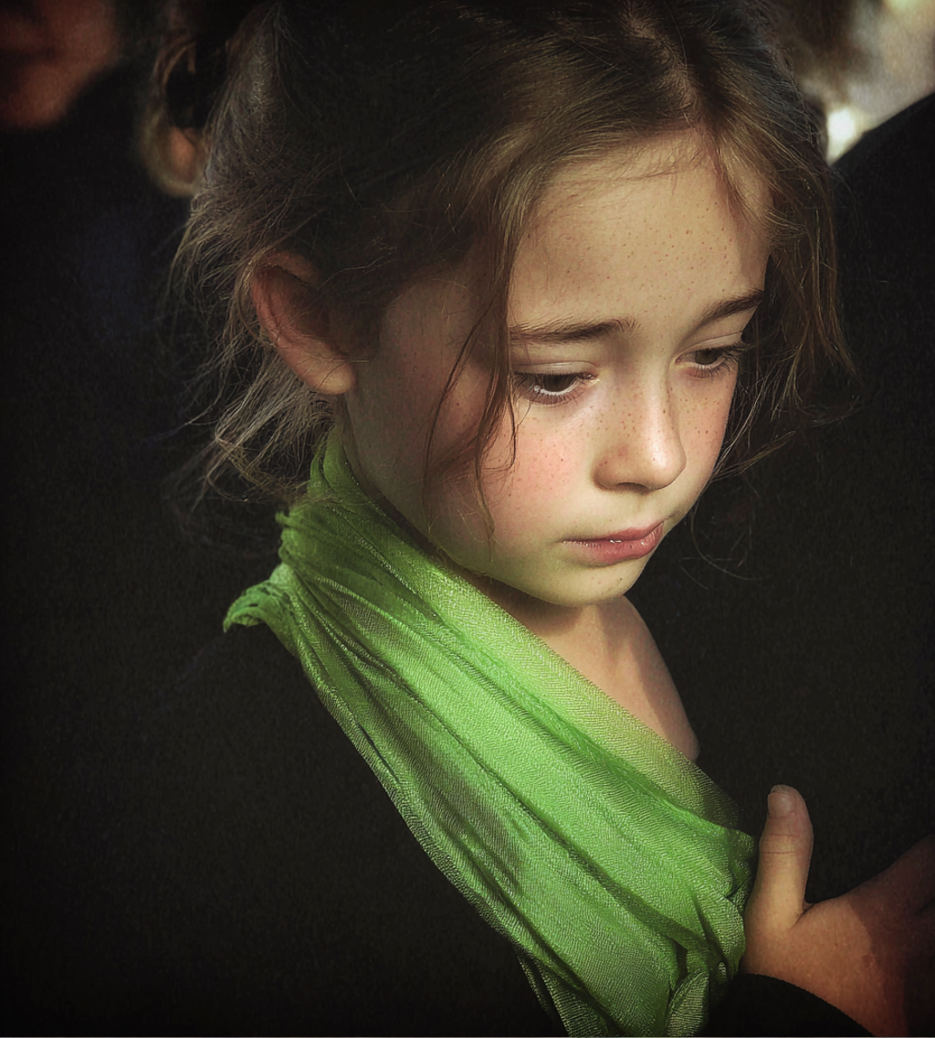 A little girl holding a green scarf | Source: Midjourney