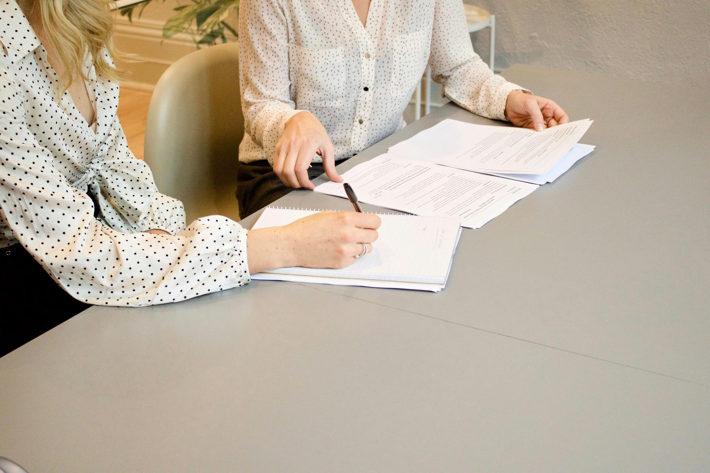 Two women sitting at a table with paperwork | Source: Unsplash