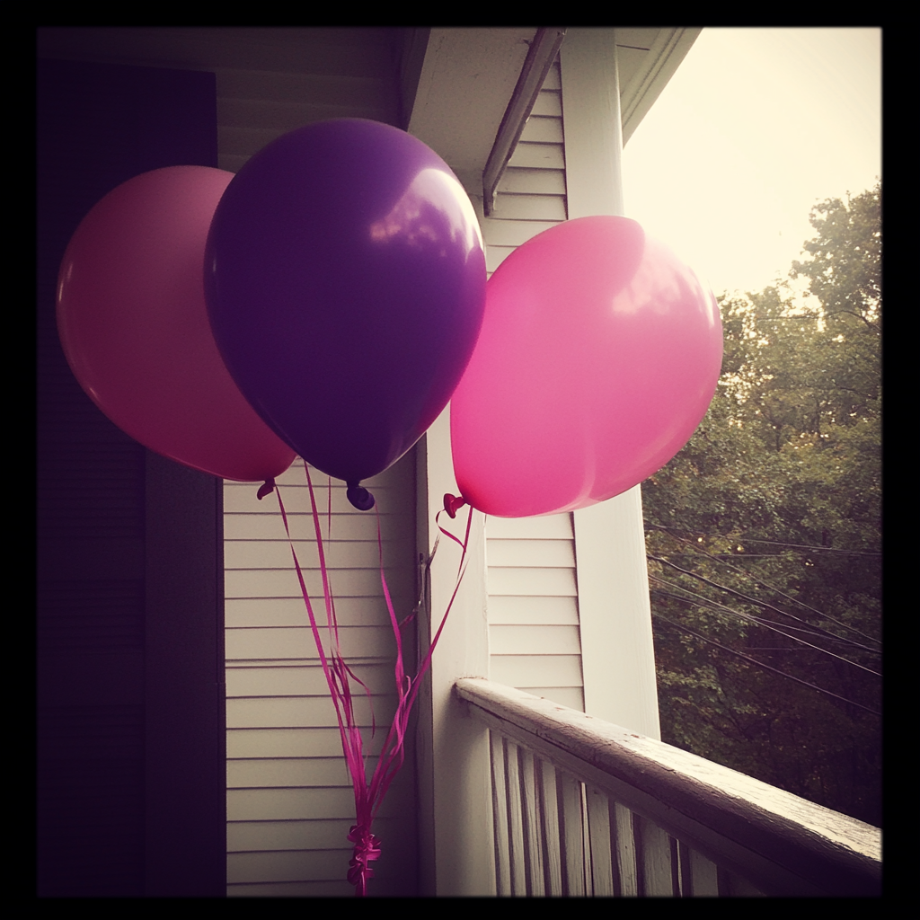 Pink and purple balloons on a porch | Source: Midjourney