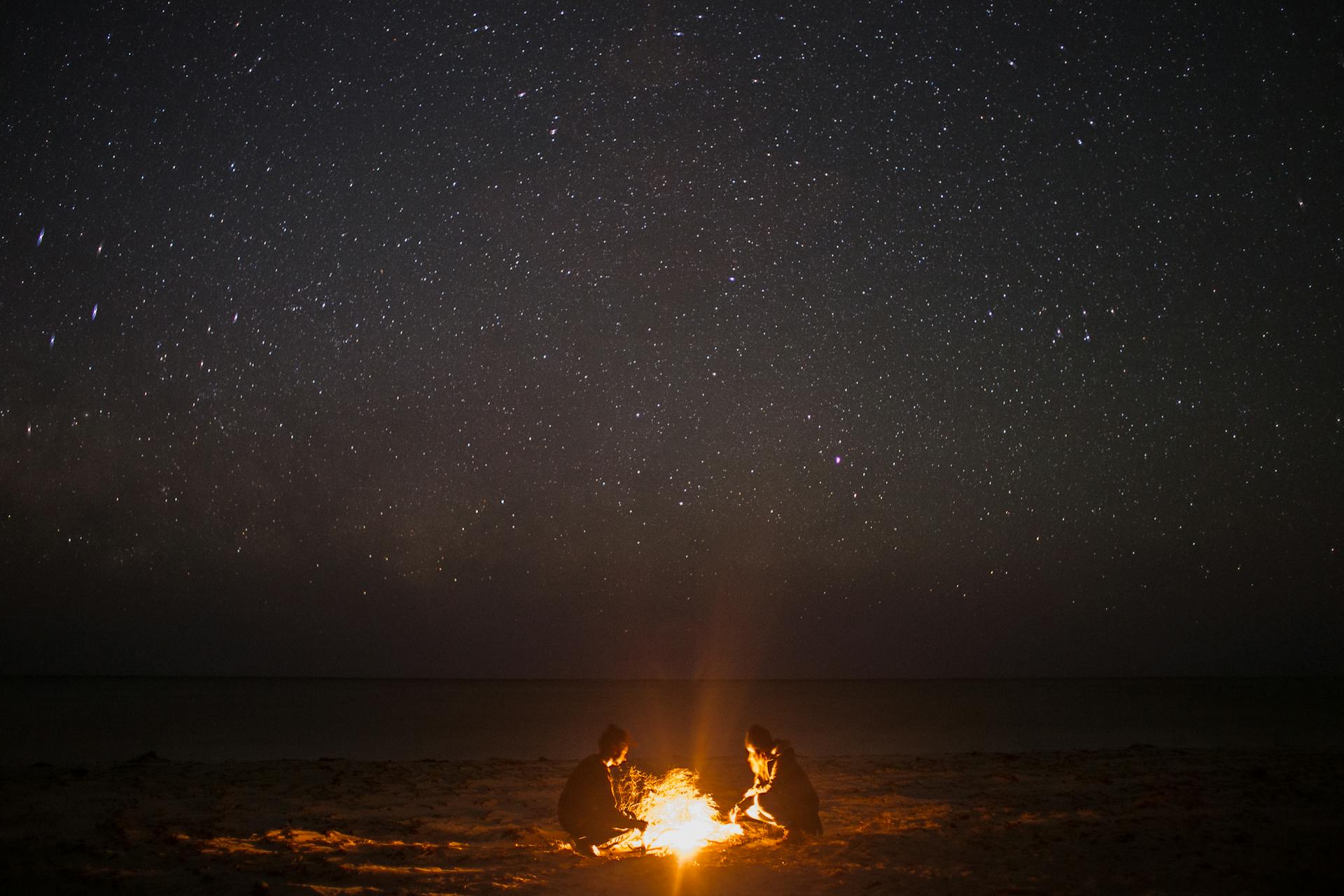 People near a bonfire on a beach at night | Source: Pexels