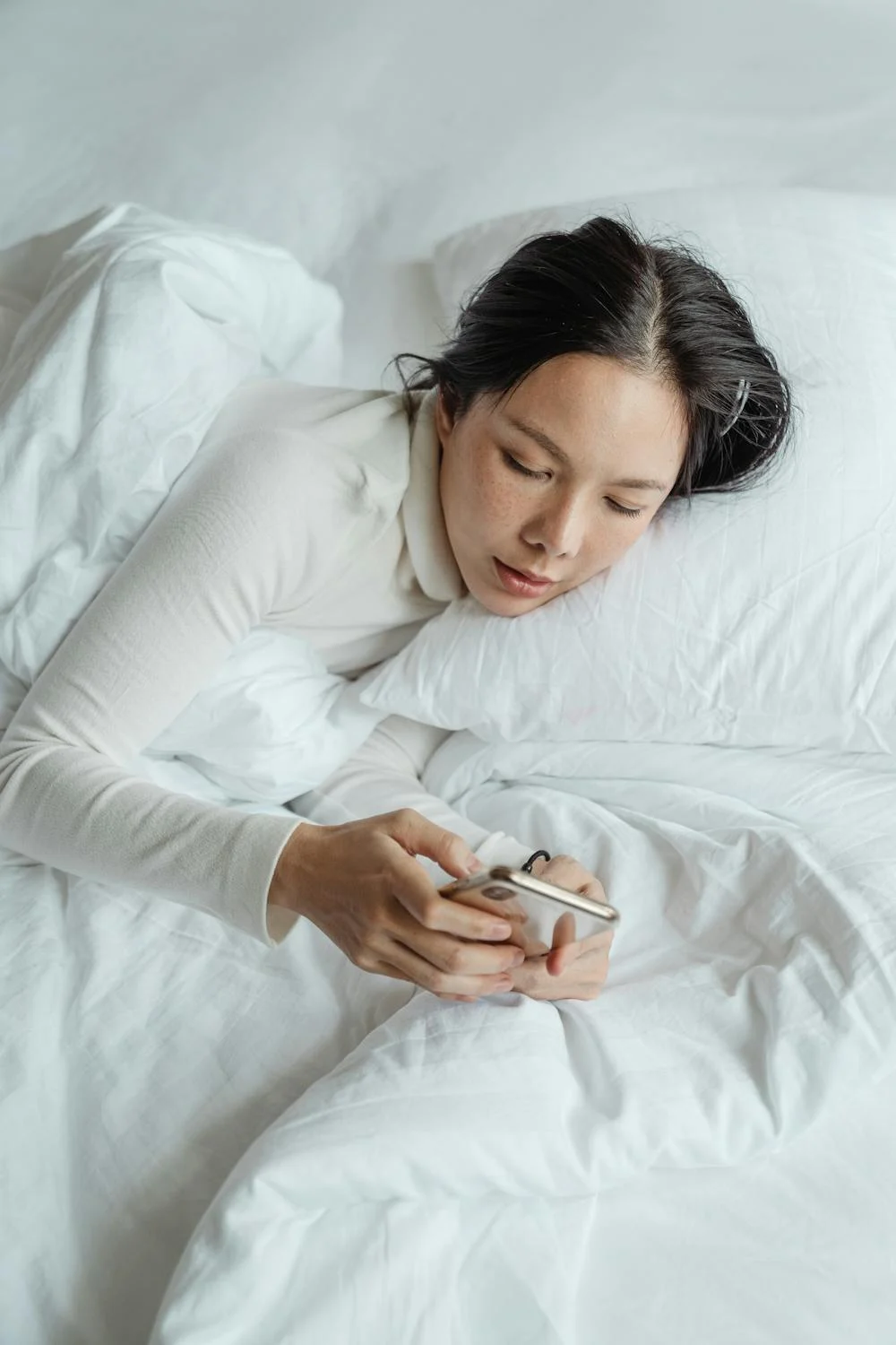 A woman texting on her phone in her bed | Source: Pexels