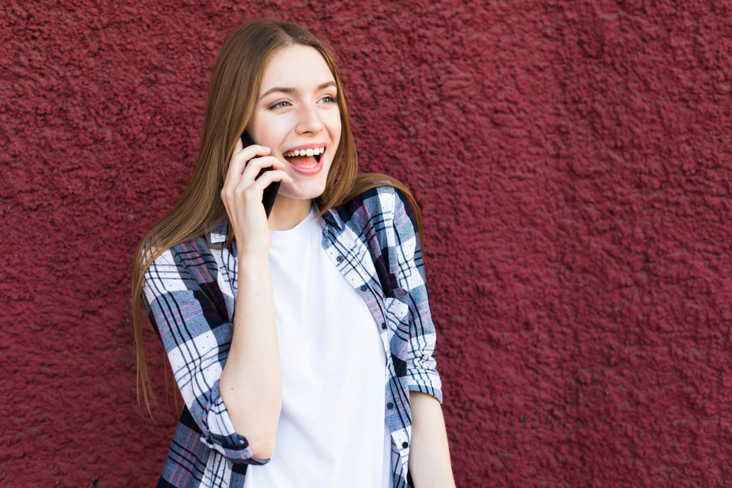 A woman laughing while talking on the phone | Source: Freepik