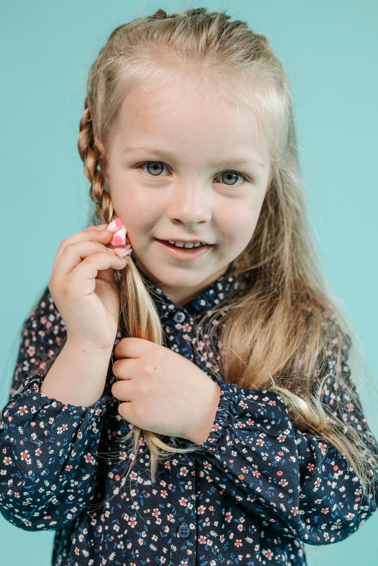 A delighted little girl holding her braided hair | Source: Pexels