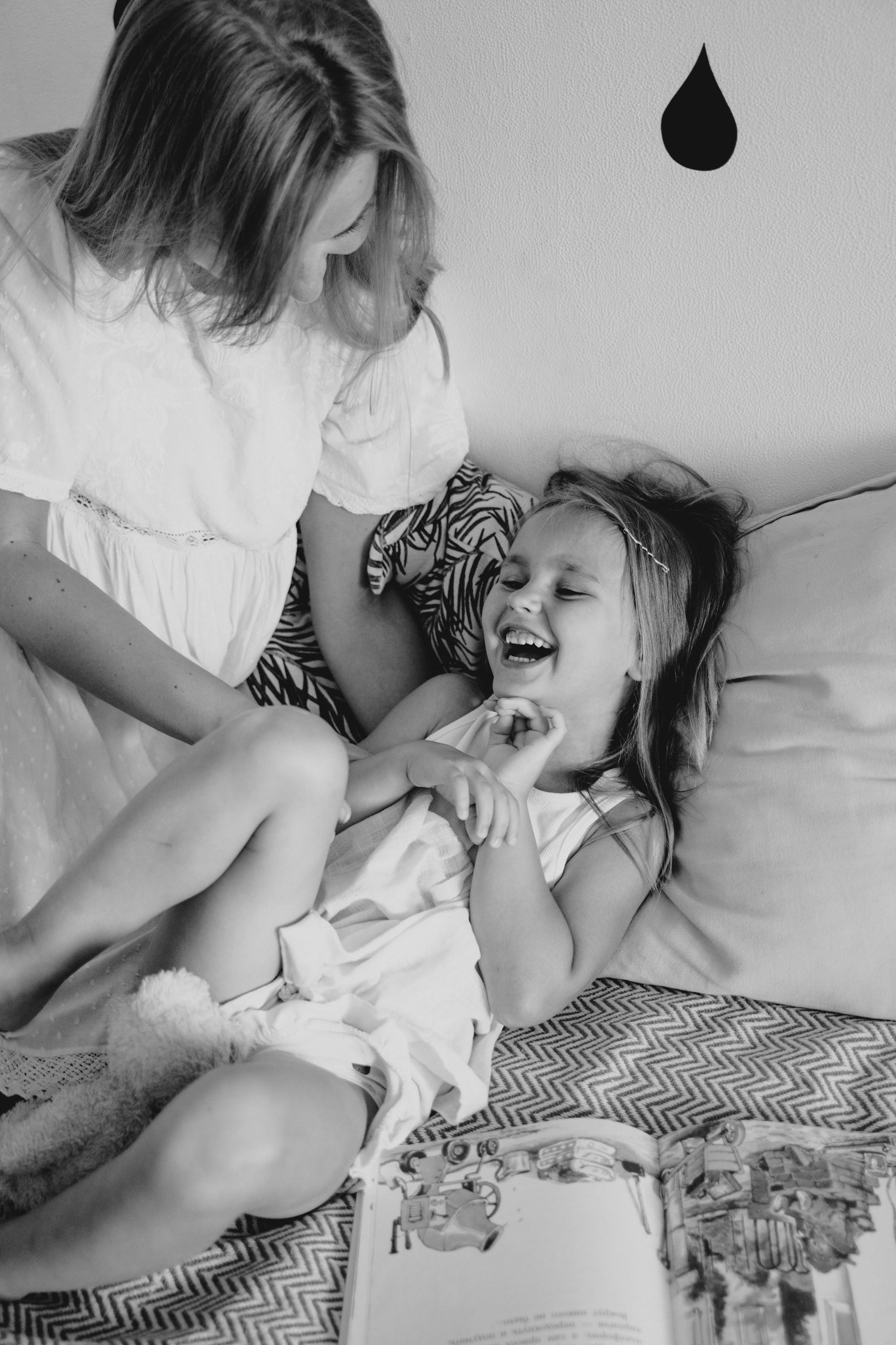 A grayscale photo of a mother tickling her little daughter | Source: Pexels