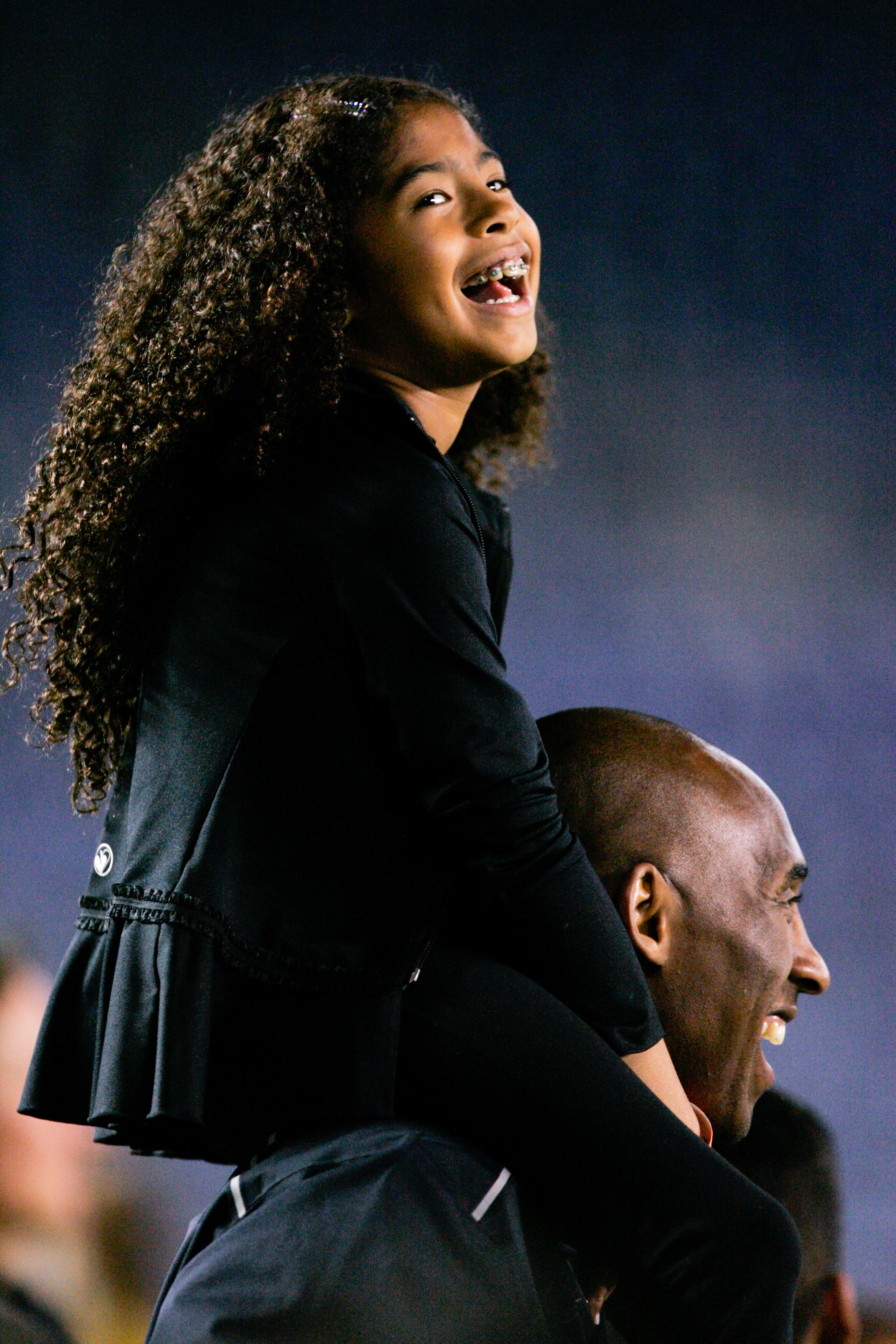 Kobe Bryant stands on the sideline with his daughter Gianna Maria-Onore Bryant on his shoulders prior to the start of the game against the United States and China during an international firendly match at Qualcomm Stadium on April 10, 2014 in San Diego, California. | Source: Getty Images