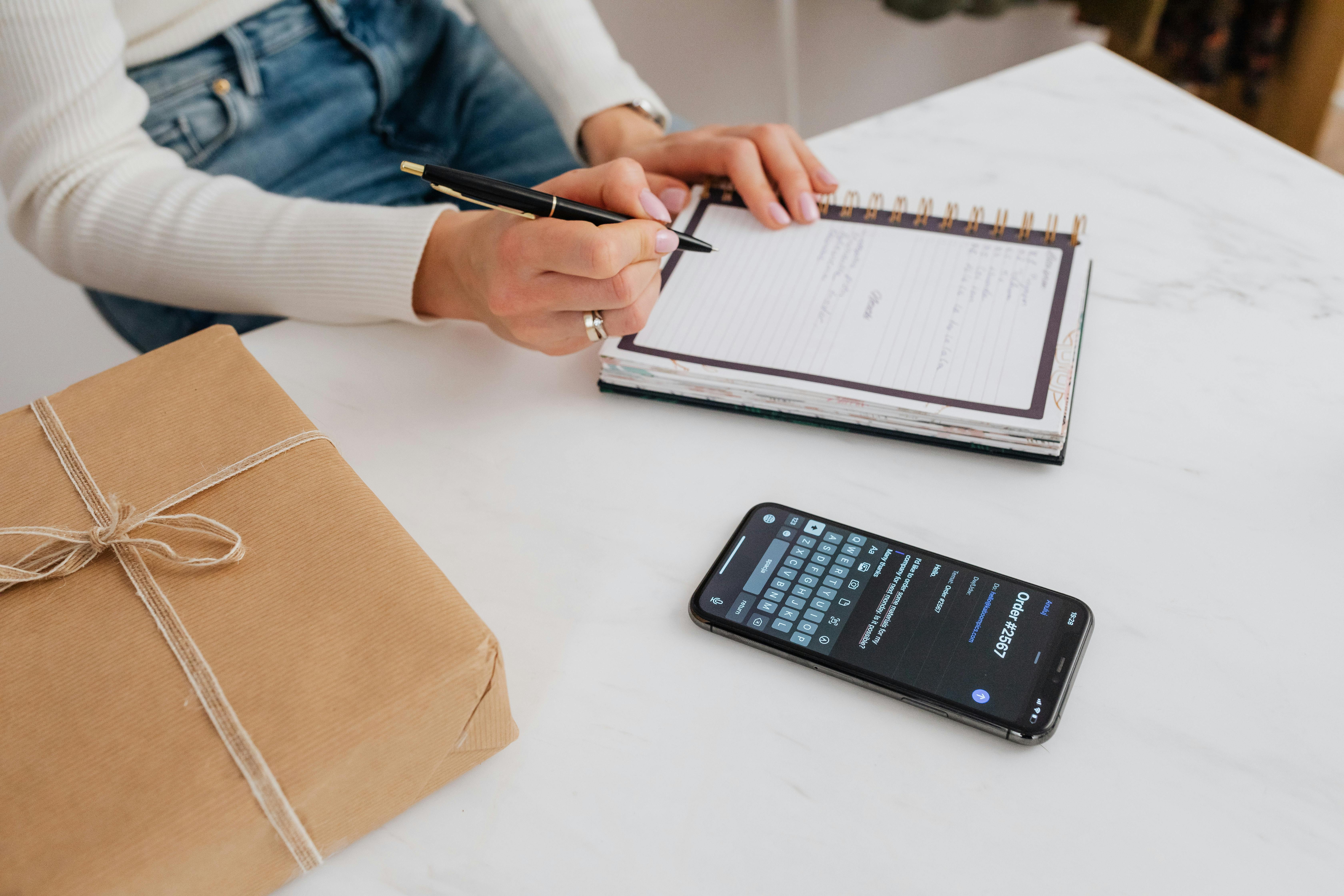 A person writing on a white notebook | Source: Pexels