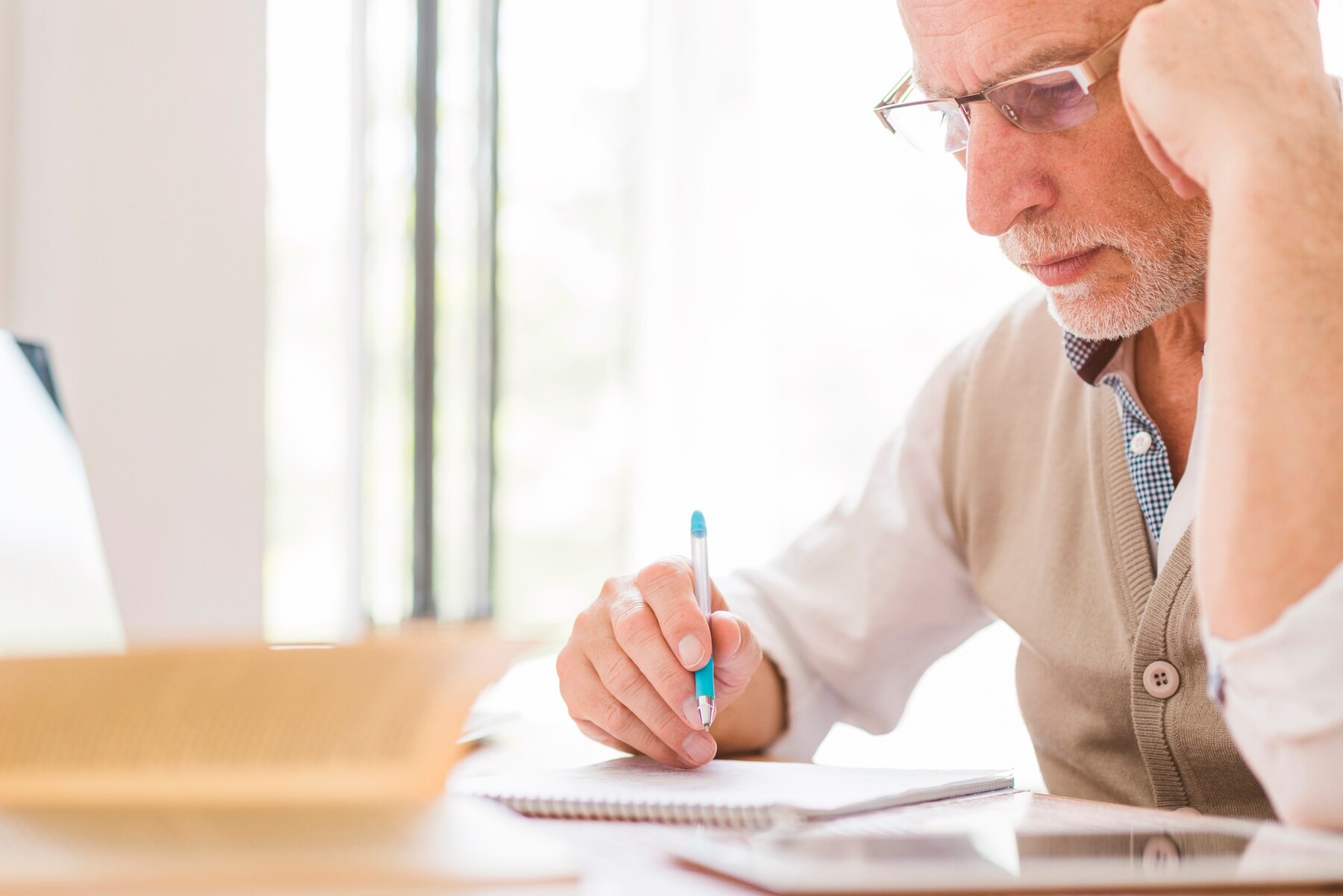 An elderly man writing | Source: Freepik