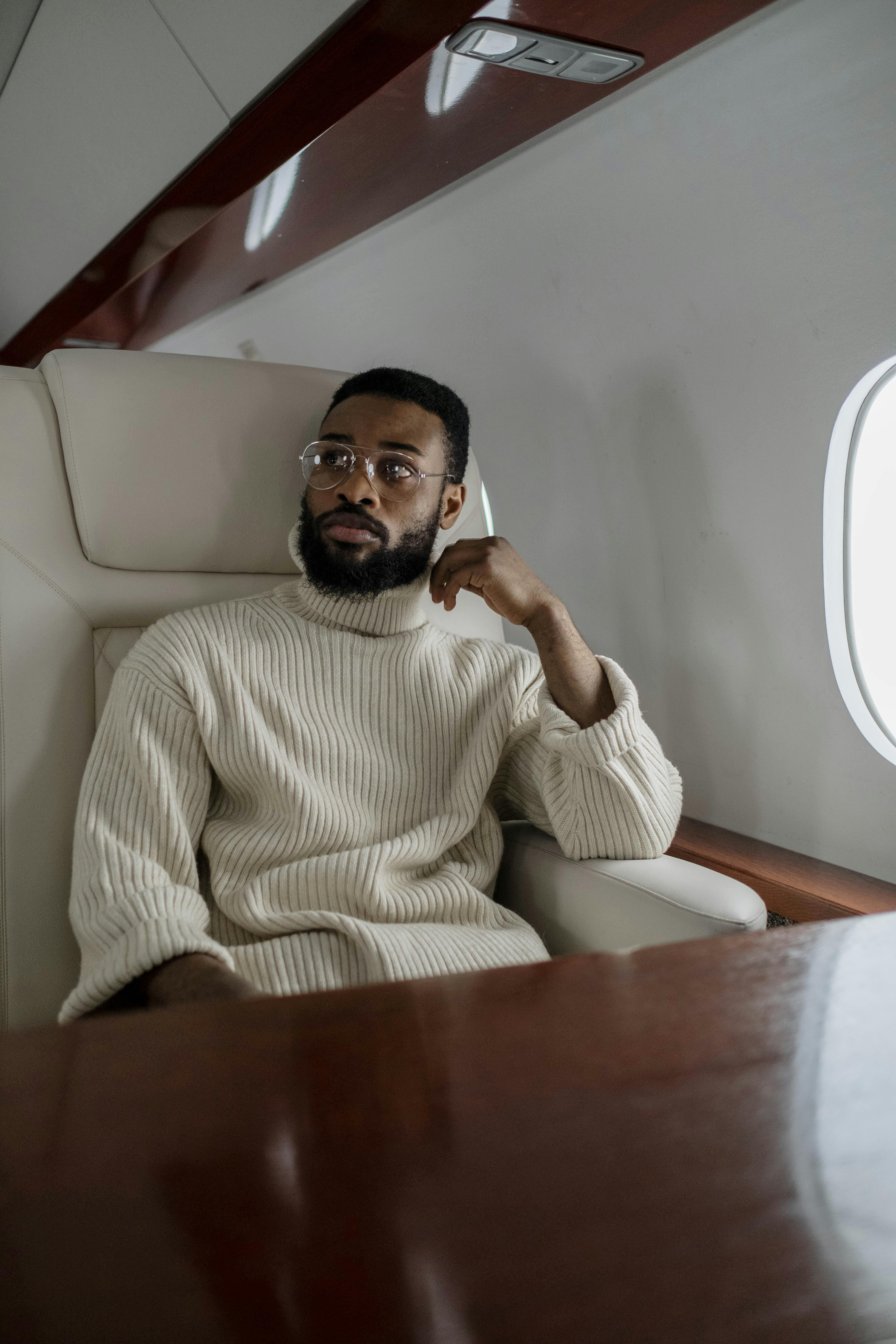 Man in a beige turtle neck sweater inside a plane | Source: Pexels