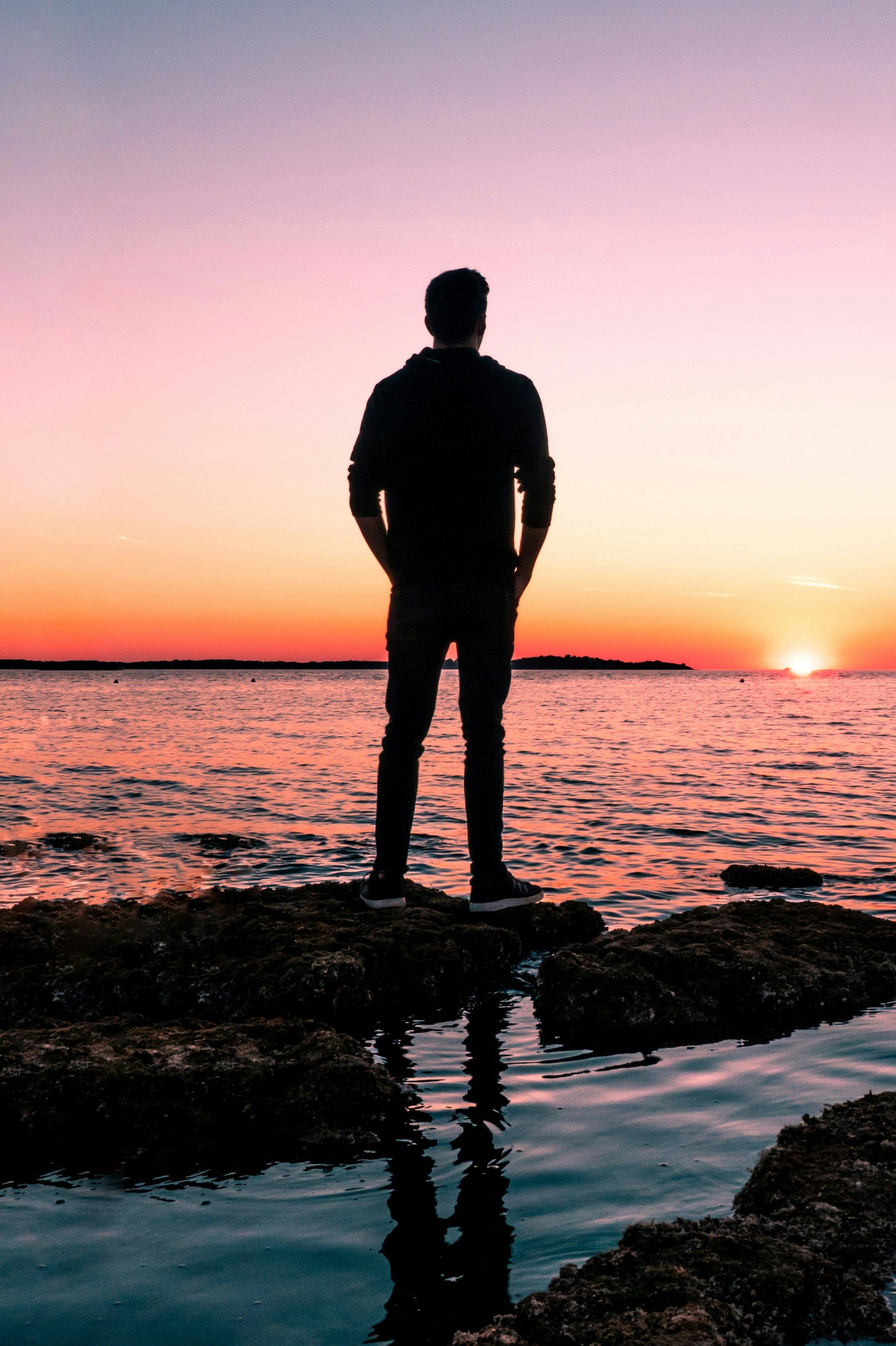 A man watching the golden sunlight from the shore on a picturesque evening | Source: Unsplash