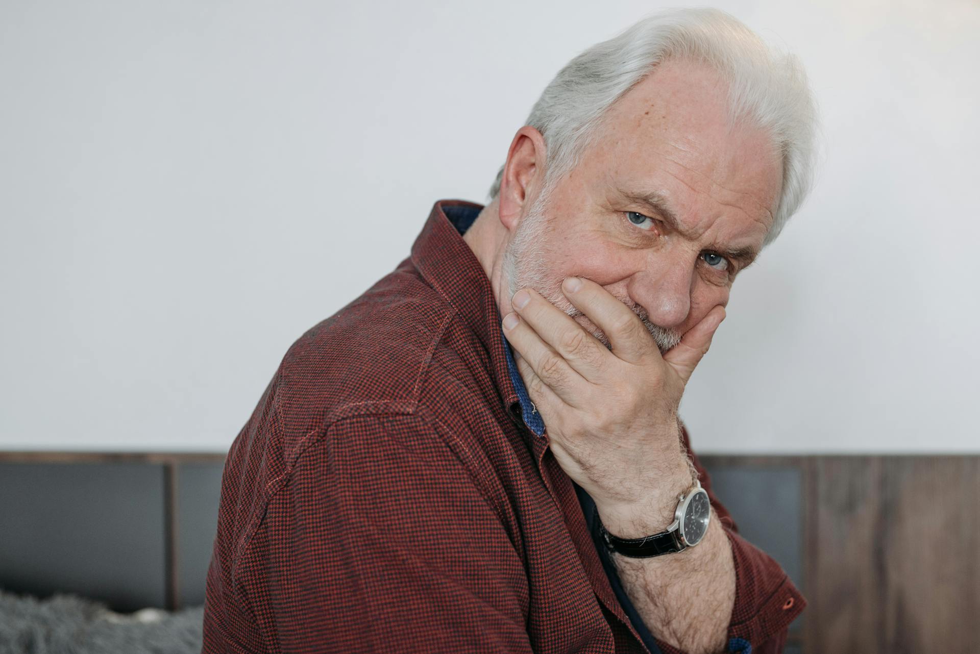 An elderly man covering his mouth with his hand | Source: Pexels