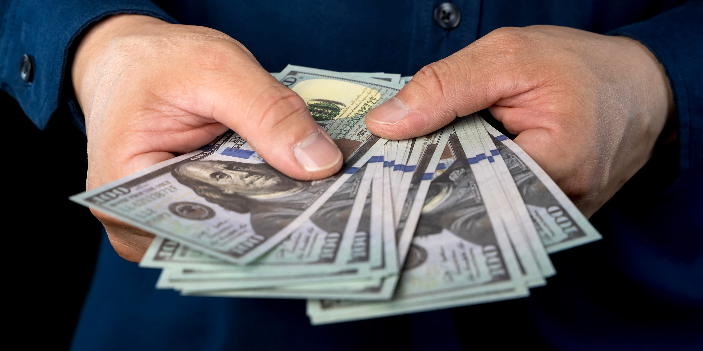 A person holding dollar bills | Source: Shutterstock