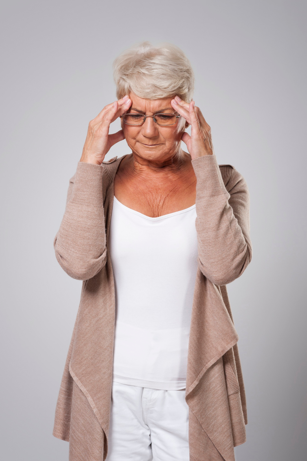 A stressed senior woman holding her head | Source: Freepik