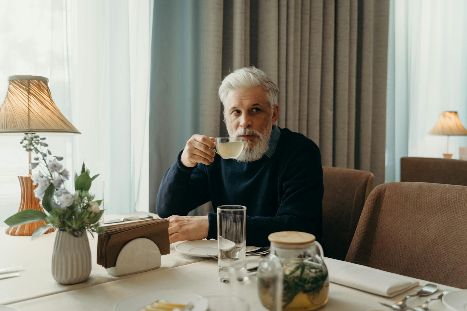 A senior man having tea while looking at someone | Source: Pexels